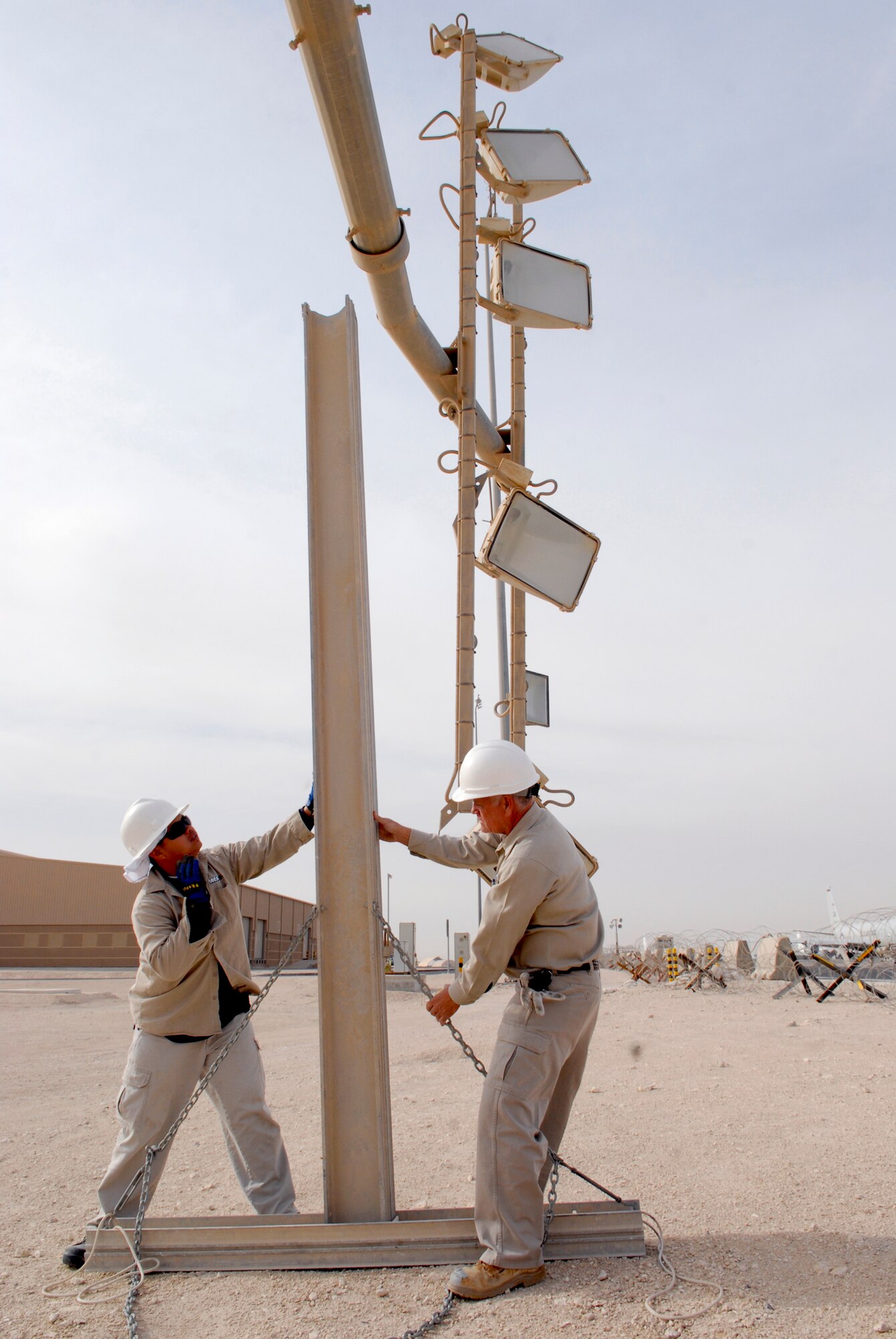 Jimmy Mercado and John Nettles, 379th Civil Engineer Squadron Readiness Management Support (RMS) Contractors, set a support stand for the ramp parking light tower to rest on while they make repairs, Mar. 4, 2009, at an undisclosed location in Southwest Asia.  Mr. Mercado hails from Santa Rita Pampanga, Philippines.  Mr. Nettles hails from McComb, Miss.  Both are here in support of Operations Iraqi and Enduring Freedom and Combined Joint Task Force - Horn of Africa.  (U.S. Air Force photo by Senior Airman Andrew Satran/released)
