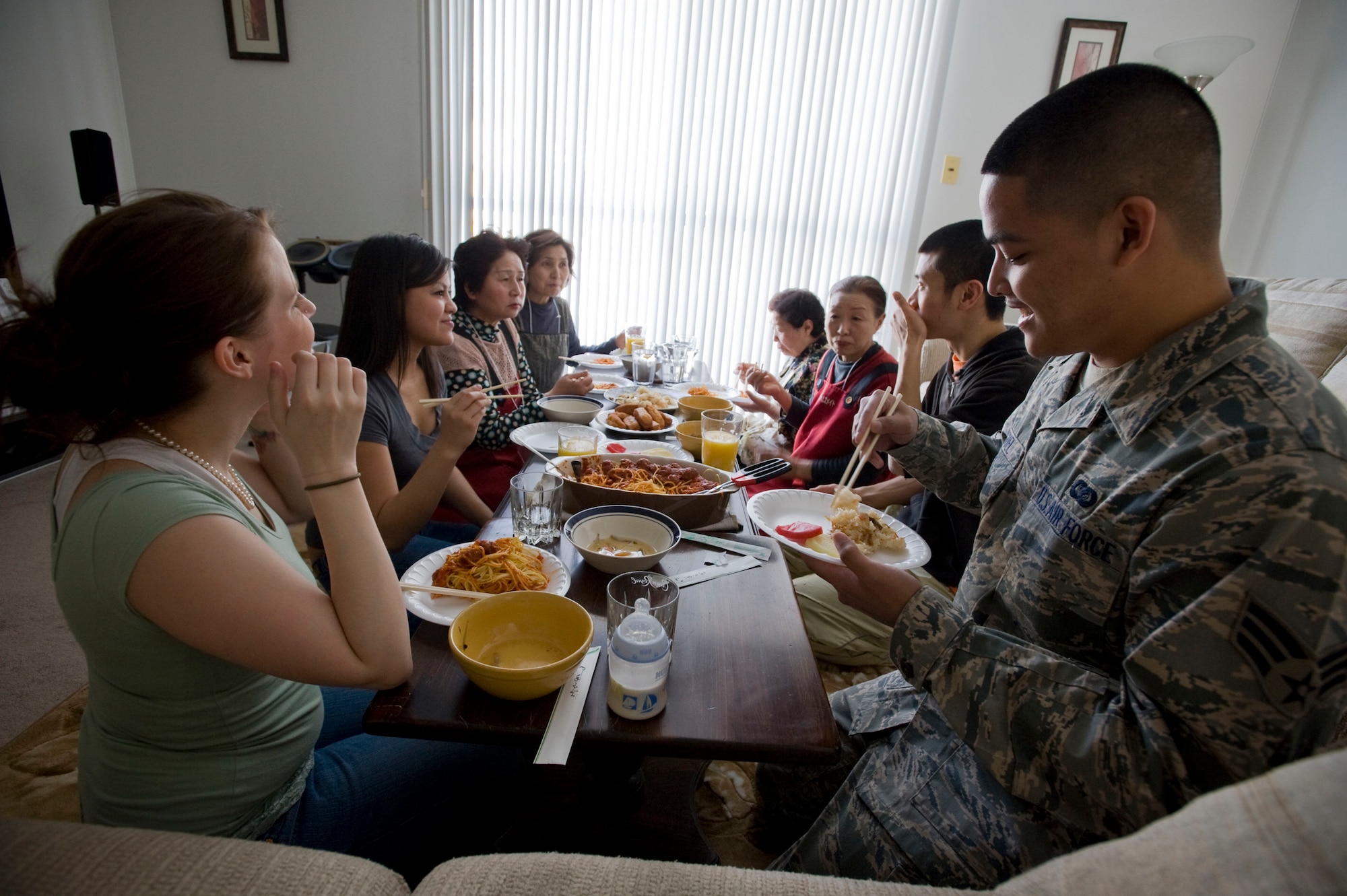MISAWA AIR BASE, Japan -- The Miguels and Japanese visitors from the Tohoku Health and Diet Improvement Program sit down to enjoy a cultural meal together March 4, 2009. To share their cooking and culture with American families, 80 Japanese women, assisted by 20 interpreters, visited Misawa Air Base homes. (U.S. Air Force photo by Staff Sgt. Samuel Morse)