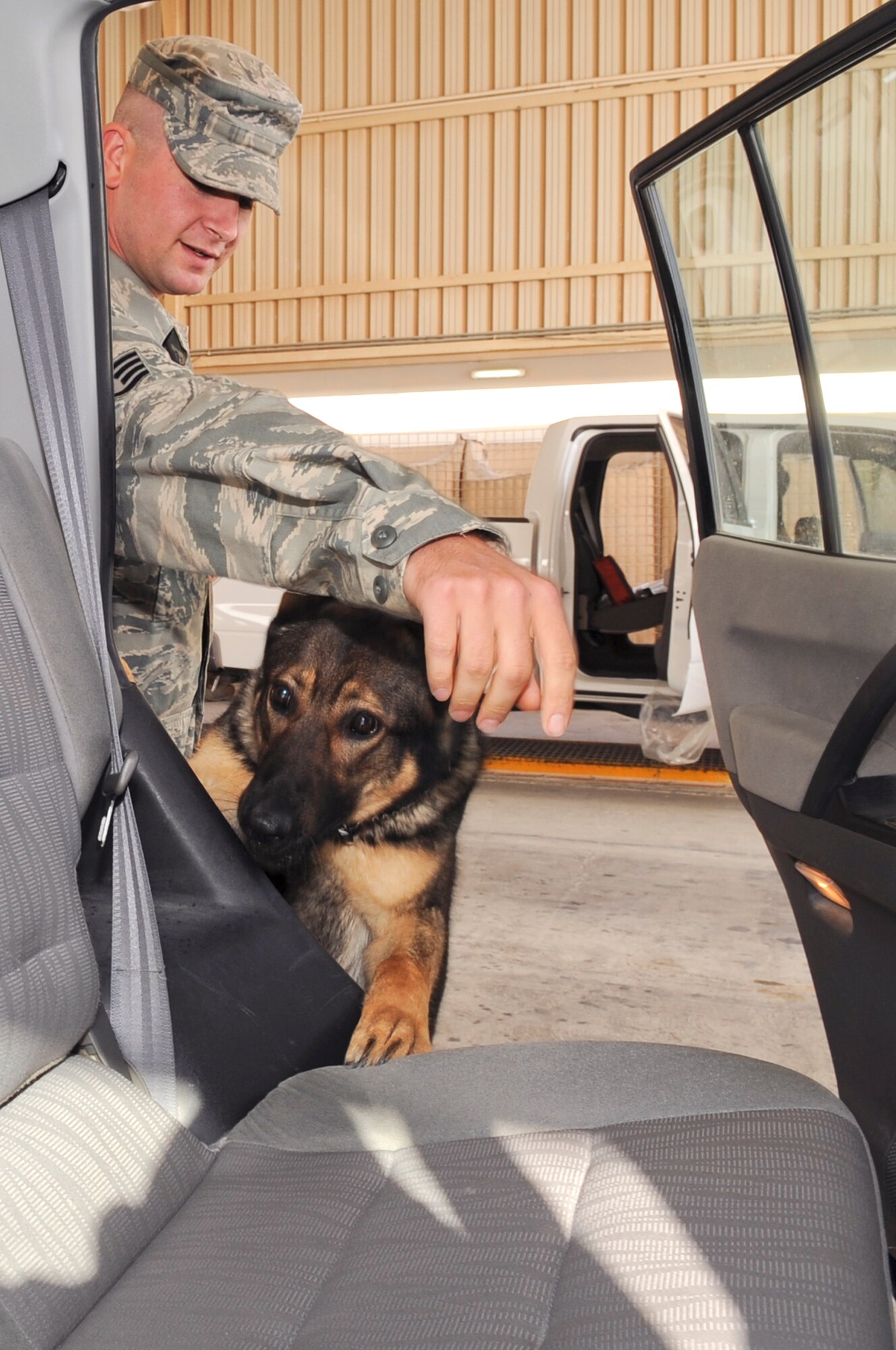 Staff Sgt. Sanford Gschwend, a K-9 handler with the 379th Expeditionary Security Forces Squadron, guides Military Working Dog Pixi through a vehicle search at the entry search pit, March 3, 2009, in an undisclosed location in Southwest Asia.  Vehicles coming from off base are searched to ensure the safety of base personnel as well as to ensure no contraband is brought in.  Sergeant Gschwend is native to Sacramento, Calif., he and Pixi are both deployed from Yokota Air Base, Japan in support of Operations Iraqi and Enduring Freedom and Combined Joint Task Force - Horn of Africa. (U.S. Air Force Photo by Staff Sgt. Joshua Garcia/released)