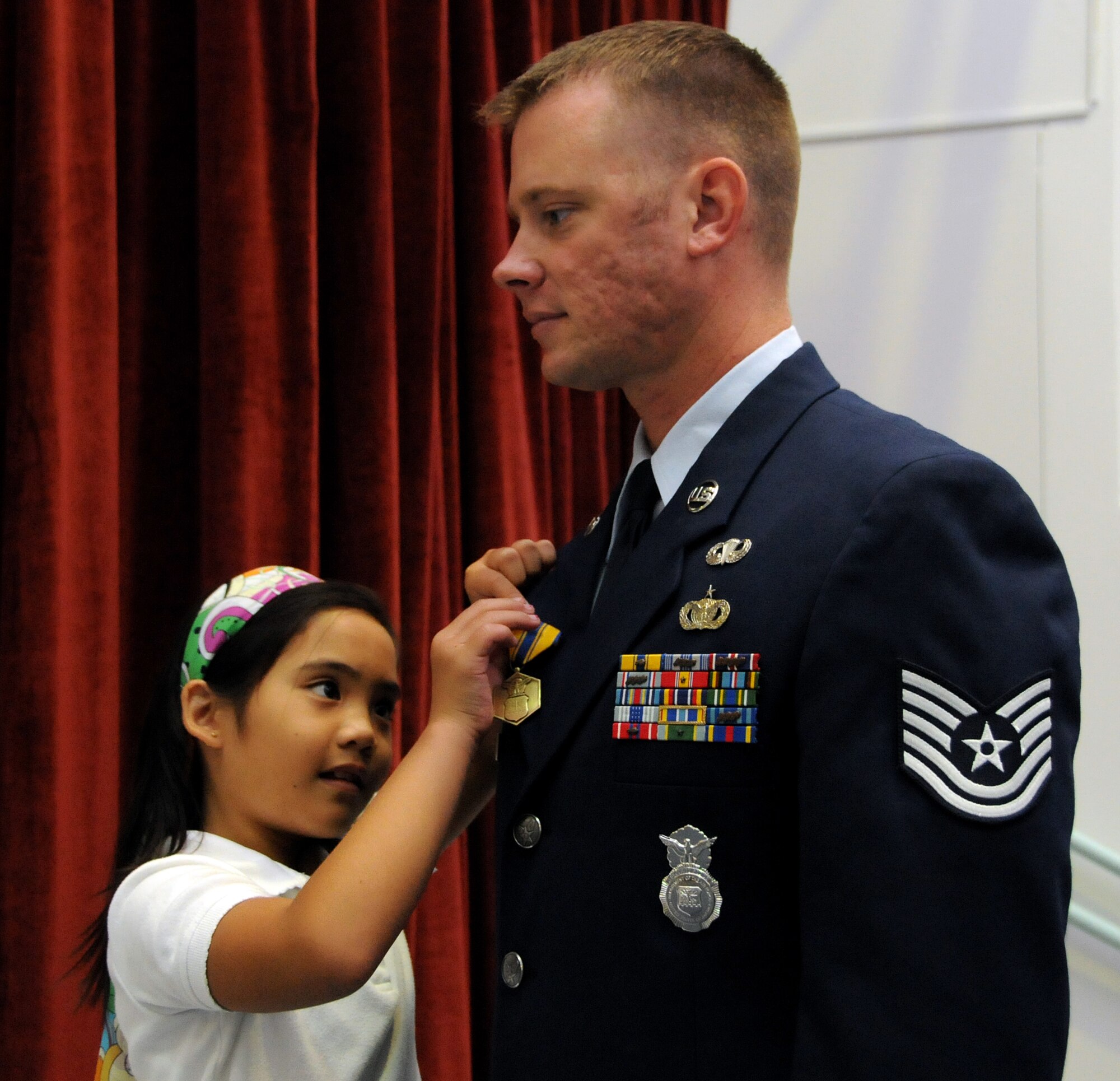 ANDERSEN AIR FORCE BASE, Guam - Jaeleen Jaylo presents Tech. Sgt. Sam Howell, 36th Security Forces Squadron, with a Commodation Medal during the Andersen Elementary School Awards Ceremony here March 4. Sergeant Howell was swimming near-by and responded immediately by diving under the water, and pulling Jaeleen out of the pool. (U.S. Air Force photo by Airman 1st Class Courtney Witt)