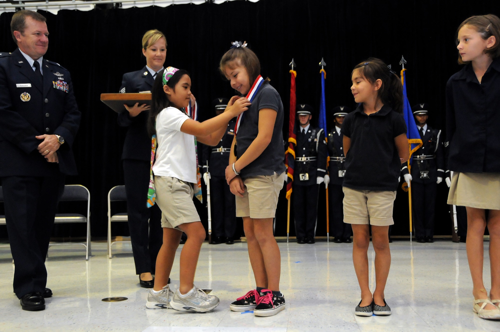 ANDERSEN AIR FORCE BASE, Guam - Jaeleen Jaylo presents Katelyn Powell with a medal that reads "Life Saver Award:  Presented to (Name).  For Your Efforts To Assist Jaeleen Jaylo on November 14, 2008" along with four other heroic girls during the Andersen Elementary School Awards Ceremony here March 4. Katelyn Powell was the first to see Jaeleen Jaylo underwater and asked her sister Mackenzie Powell to dive down and see what was happening. Mackenzie was not strong enough to move Jaeleen, so she returned to the surface to inform her sister, who then asked Brooke Hummel to see if she could retrieve her from the bottom. These young ladies -- these young heroes were very instrumental to saving Jaeleen's life.(U.S. Air Force photo by Airman 1st Class Courtney Witt)
