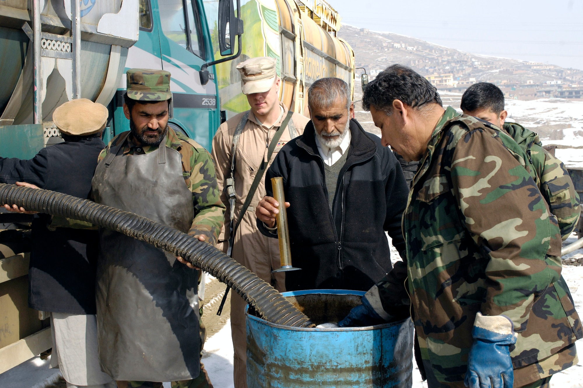 Afghanistan national army Lt. Col. Mohammad Adris captures fuel in a clear glass coffee mug as its offloaded from a fuels truck prior to accepting delivery Feb. 17 at Khuja Rawash in Kabul, Afghanistan. The inspector raises the mug, once full, looking for sediment. Colonel Adris is an operations officer and fuels tester. (U.S. Air Force photo/Maj. Carie A. Parker) 
