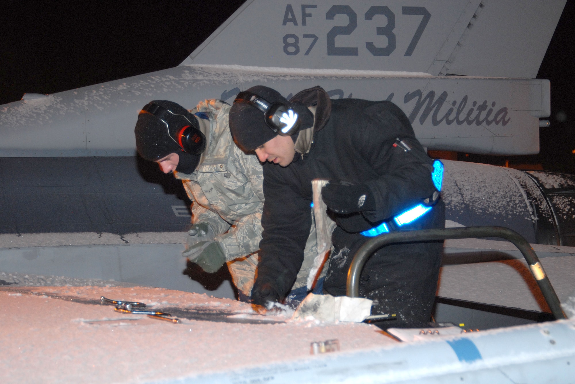 A1C Austin Smith and SSgt Brandon Ginn of the 140th Wing Maintenance section fasten down a panel on an F-16C aircraft as part of the Generation phase of the Operational Readiness Inspection.  (Photo by SMSgt John Rohrer, 140th Wing Public Affairs)