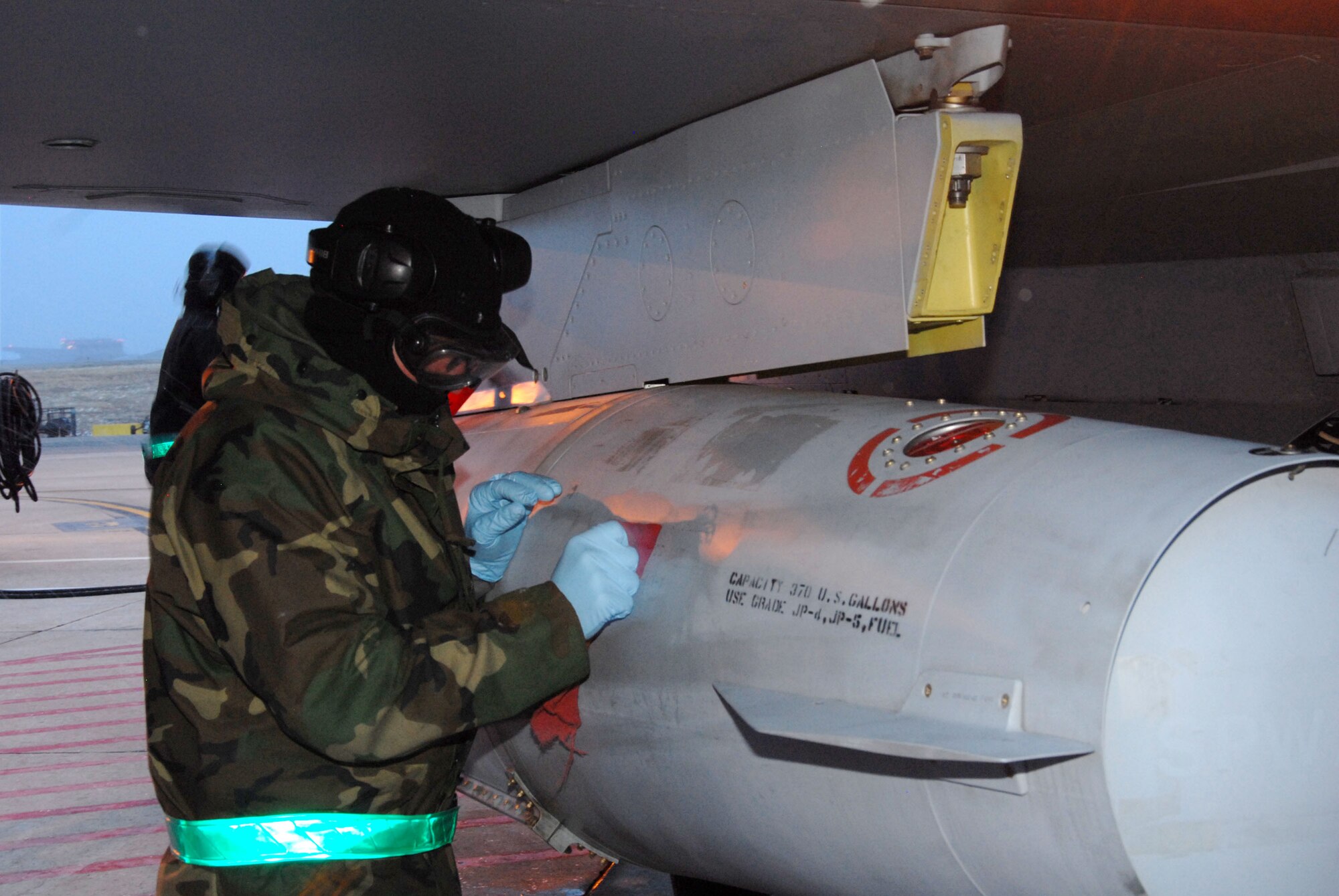 Phase Dock personnel wipe down a fuel tank on an F-16C model aircraft during an Operational Readiness Inspection at the 140th Wing, Colorado Air National Guard.  As part of the generation phase of the inspection, members braved the cold and snow as they ensure that all required aircraft are ready to deploy to a mock forward operation base.  (Photo by SMSgt John Rohrer, 140th Wing Public Affairs)