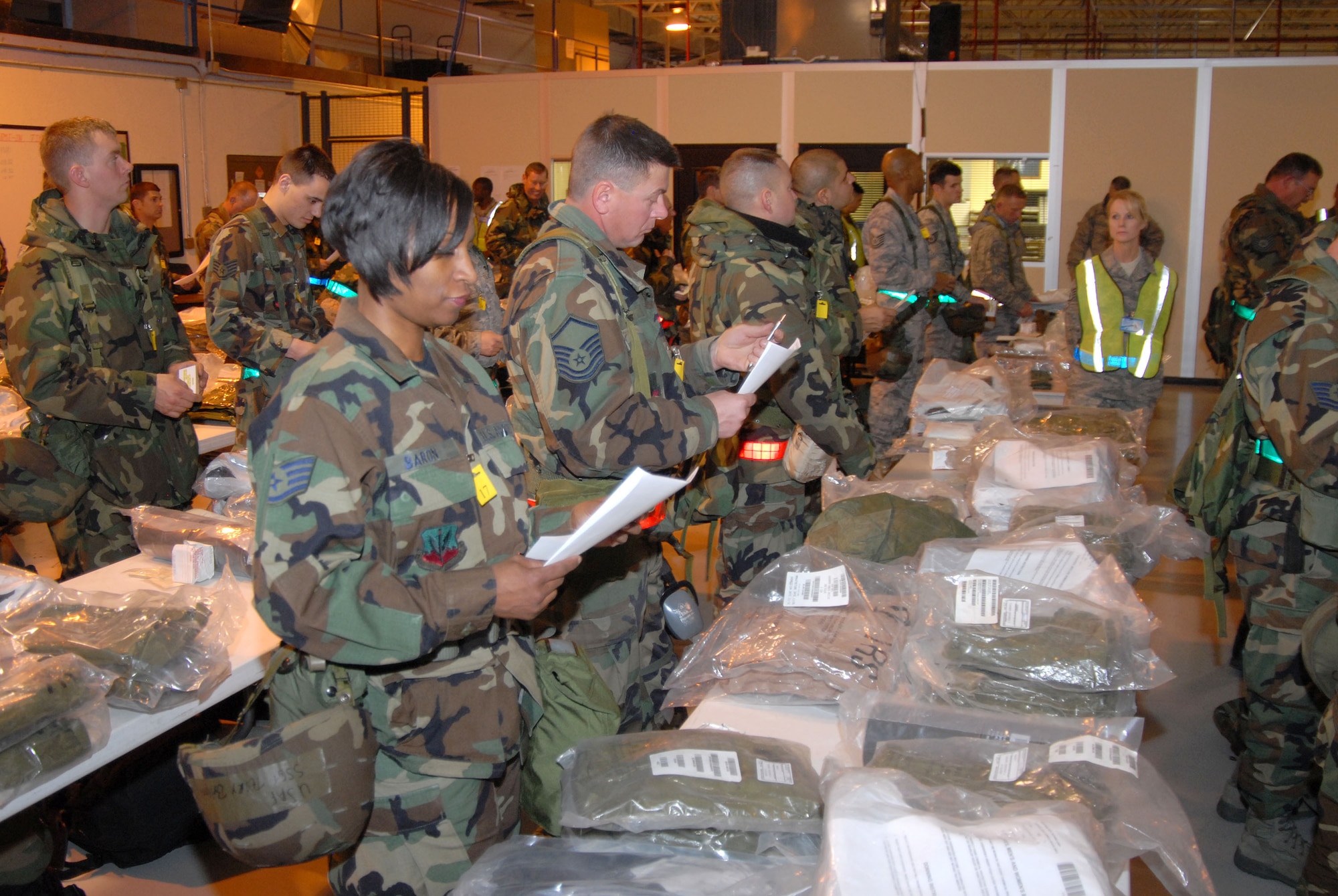 SSgt Terry Baron, SrA Gregory Swaisgood, MSgt Mark Caton, SSgt Troy Lippelt, SSgt Richard Martinez and others inventory their C-bags as SSgt Vicky Perreault observs during an Operational Readiness Inspection at the 140th Wing.  This is part of the processing that is required as  members prepare to deploy.  (Photo by SMSgt John Rohrer, 140th Wing Public Affairs)