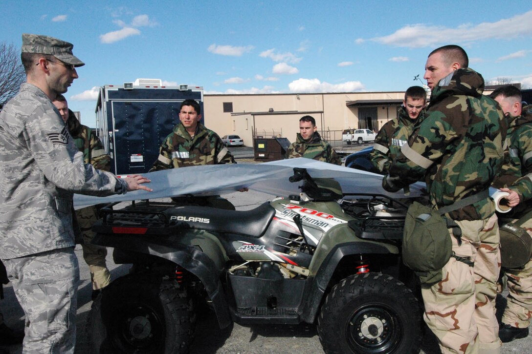 Staff Sgt. Jason Blair, 316th Civil Engineer Squadron logistics NCO in charge and emergency management technician, left, gives guidance to a group of 89th Airlift Wing members on how to cover an all-terrain vehicle prior to a chemical biological warfare attack, during an Operational Readiness Inspection training session Feb. 19. The 89 AW deployed a 37-member team to Travis Air Force Base, Fairfield, Calif. March 1, for a week-long ORI. (U.S. Air Force photo/Bobby Jones)