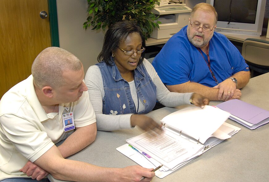 Deborah Burge reviews safety binders with Robert Lewis, medical group assistant facility manager, left, and Tilford Bowlan, medical instrument technician and unit safety representative, after a recent fire drill in Occupational Health, Bldg. 3334. Ms. Burge’s continuous efforts to educate medical group personnel on safety have earned her a Voluntary Protection Program pat on the back. (Air Force photo/Margo Wright) 
