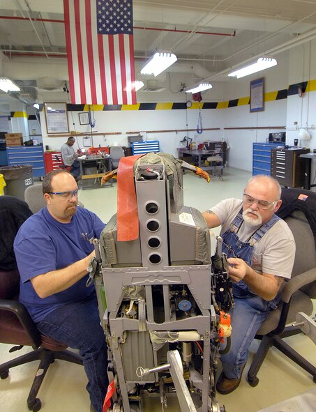 Jeff Hand, left, and Stan Jackson put an ACES II B-1 seat back together after preventive maintenance. Each seat holds 14 miniature explosive devices that synchronize in an emergency to help propel a strapped-in crew member from a doomed aircraft at zero to 80 miles per hour in approximately two seconds.(Air Force photo by Margo Wright) 