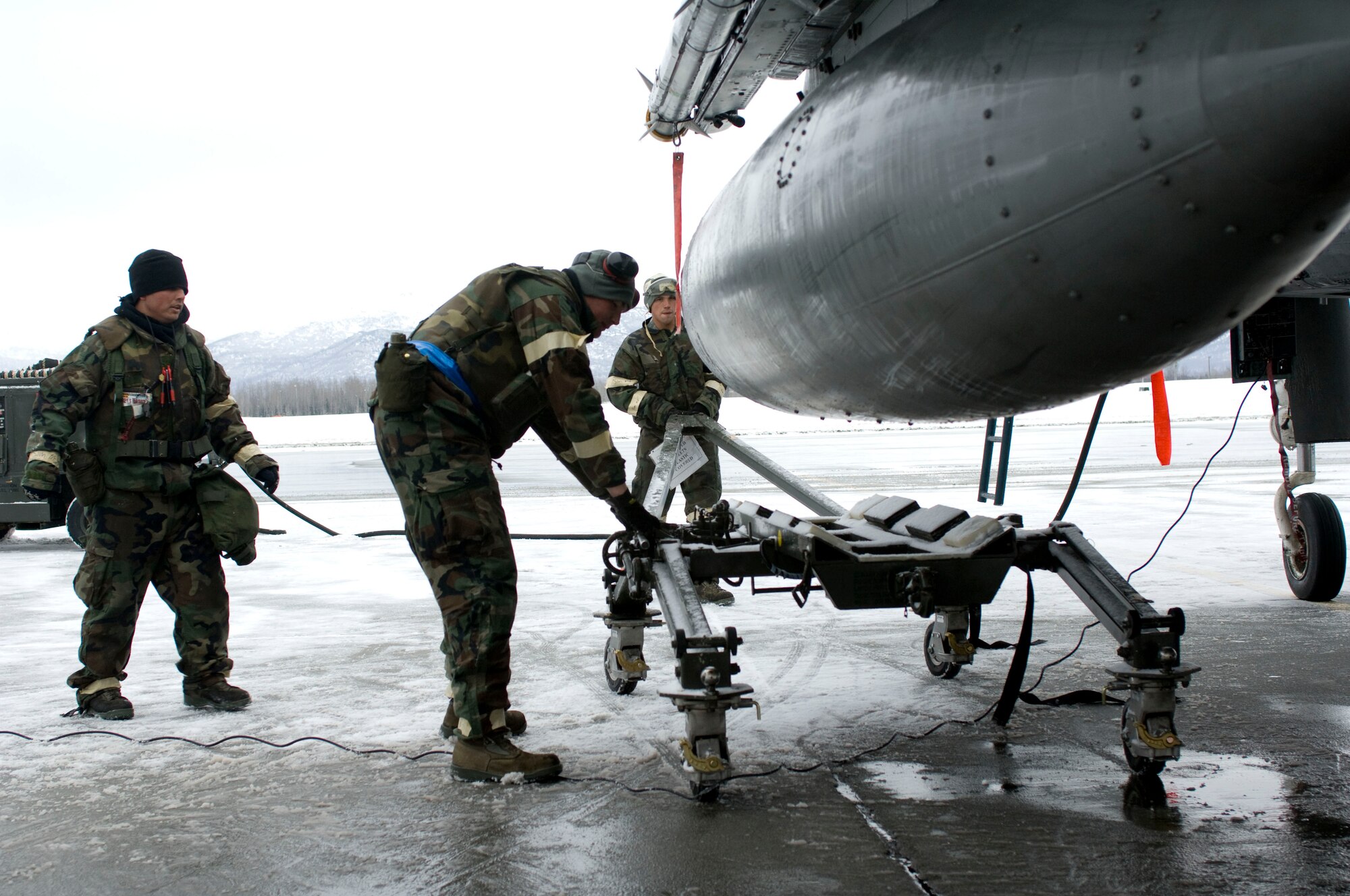 ELMENDORF AIR FORCE BASE, Alaska -- Airmen from the 19th Aircraft Maintenance Unit push a trailer underneath an external fuel tank during Polar Force 09-3, an operational readiness exercise, March 5, 2009. The 3rd Wing evaluated Airmen on their ability to survive in combat situations during deployments for the ORE. (U.S. Air Force photo by Senior Airman Jonathan Steffen)