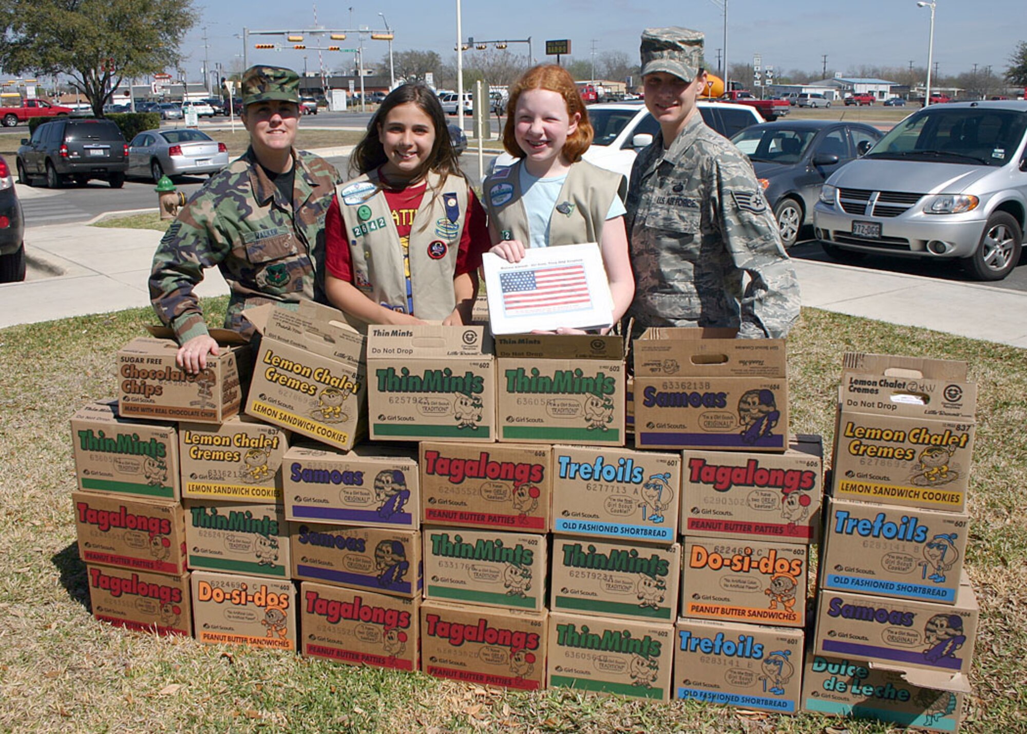 Tech. Sgt. Shauna Walker and Staff Sgt. Sunshine Scarbrough (far right), Air Force Personnel Center community outreach coordinators, receive 515 boxes of Girl Scout cookies from Samantha Frank and Madison Albrecht, Girl Scout Troop 2642 members, March 4 at Randolph Air Force Base, Texas. The 12-year-old girls raised the money to purchase the cookies from local businesses and community members. Each box has an original poem written by Albrecht thanking the servicemembers for their sacrifice and service to the nation. These cookies will be shipped to deployed servicemembers in Iraq, Afghanistan, and other countries in the Middle East. This is the second year Albrecht has raised money to purchase Girl Scout cookies for deployed servicemembers.