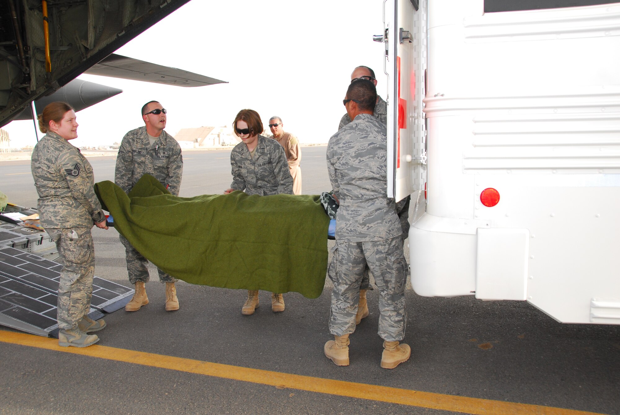 SOUTHWEST ASIA -- Personnel from the 386th Expeditionary Medical Group litter carry a wounded Soldier from an aircraft to the back of their patient transport bus at an air base in Southwest Asia, March 1. Once loaded on the bus the patients are then transported to the Contingency Aero Medical Staging Facility to wait for further transport. (U.S. Air Force photo/ Senior Airman Courtney Richardson) 