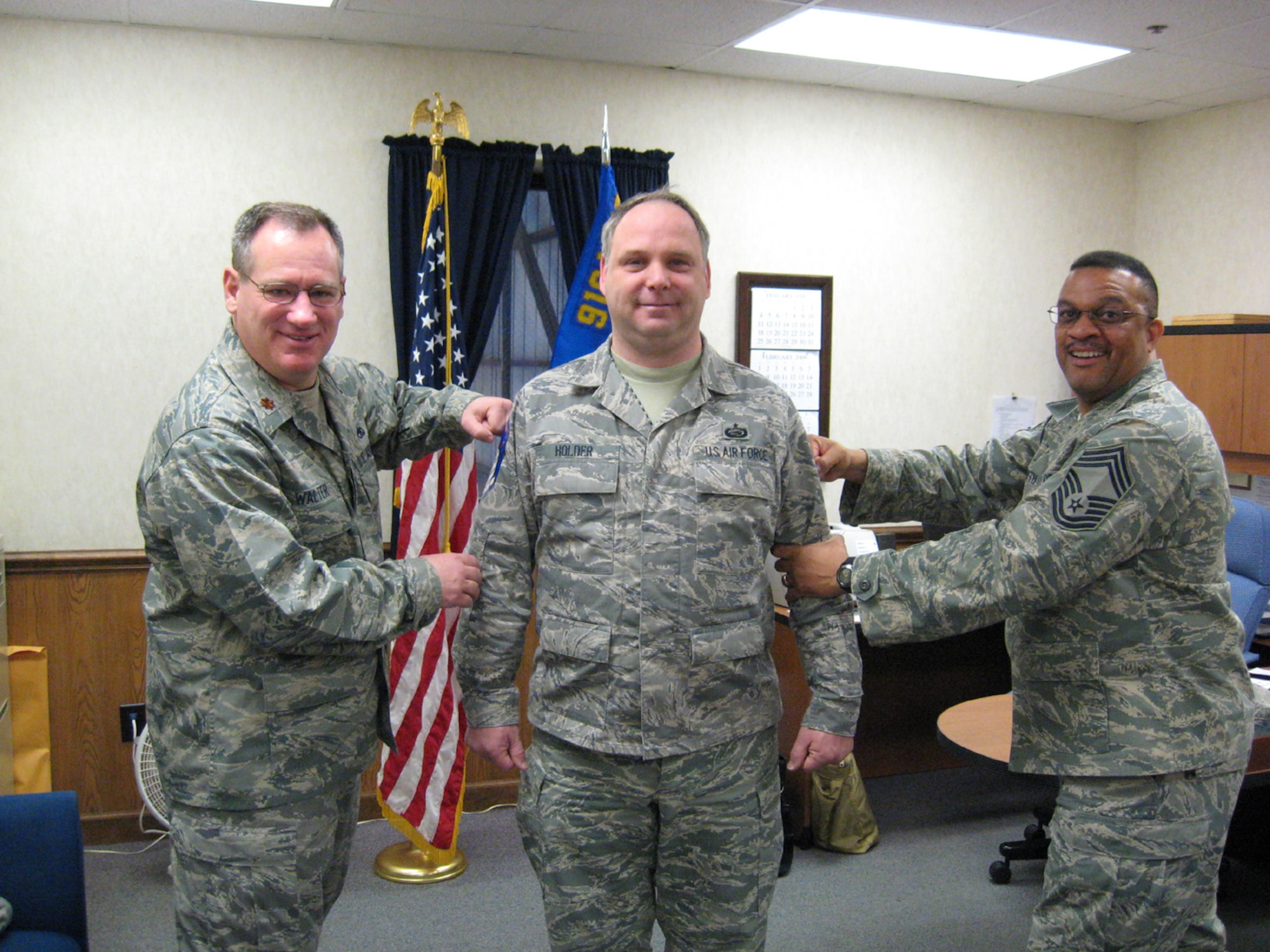 SEYMOUR JOHNSON AIR FORCE BASE, N.C. -- Air Force Reservist Brett Holder, center, is promoted to the rank of master sergeant during the February unit training assembly. Maj. Thomas Walter (left) and Chief Master Sgt. Kenny Smith (right) do the honoring of 'tacking on' Sgt. Holder's new stripes. All three reservists work with the 916th Maintenance Group.