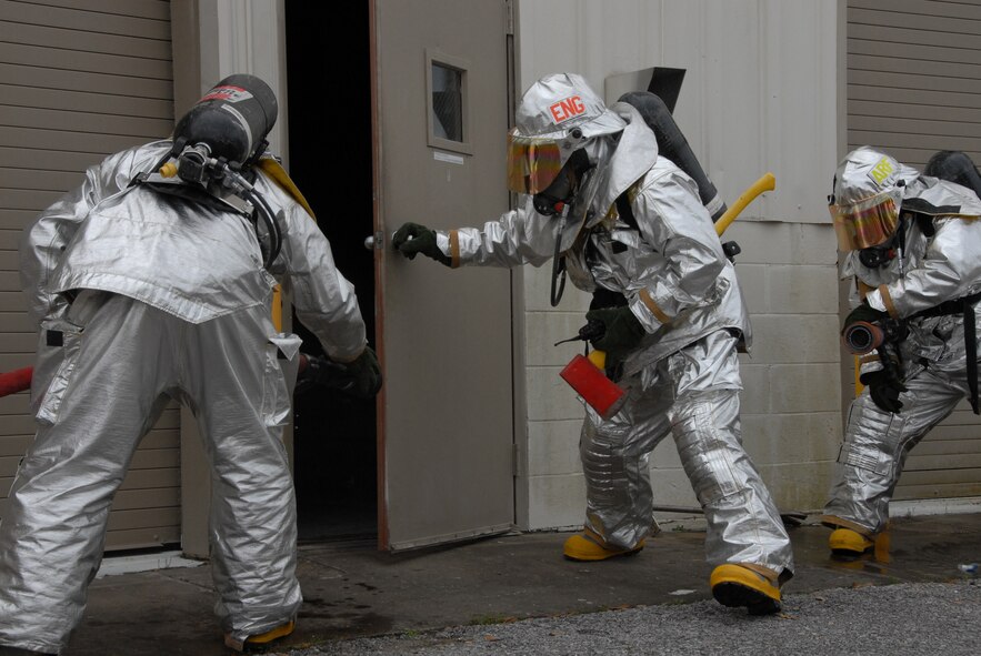 A firefighter with the 919th Civil Engineer Squadron, opens the door of a simulated burning building as two hose-teams prepare to enter during a fire exercise March 7 at Duke Field.  The exercise, performed as part of the Unit Compliance Inspection, had the firefighters secure the scene, put out the fire, evacuate victims and set up a triage.  The entire scenario lasted less than 15 minutes, with two teams entering the building and evacuating two simulated victims.  U.S. Air Force photo / Staff Sgt. Samuel King Jr.