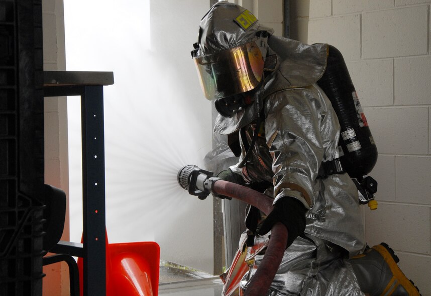 A firefighter with the 919th Civil Engineer Squadron keeps water on the flame while a team evacuates a victim during a simulated burning building exercise March 7 at Duke Field.  The exercise, performed as part of the Unit Compliance Inspection, had the firefighters secure the scene, put out the fire, evacuate victims and set up a triage.  The entire scenario lasted less than 15 minutes, with two teams entering the building and evacuating two simulated victims.  U.S. Air Force photo / Staff Sgt. Samuel King Jr.