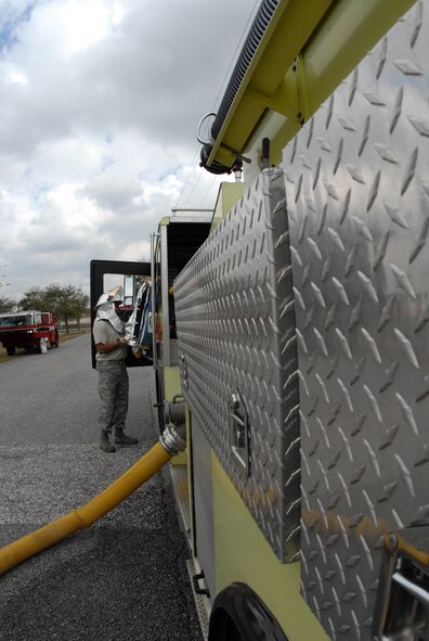 A firefighter removes his gear at the fire engine after a fire exercise March 7 at Duke Field.  The exercise, performed as part of the Unit Compliance Inspection, had the firefighters secure the scene, put out the fire, evacuate victims and set up a triage.  The entire scenario lasted less than 15 minutes, with two teams entering the building and evacuating two simulated victims.  U.S. Air Force photo / Staff Sgt. Samuel King Jr.