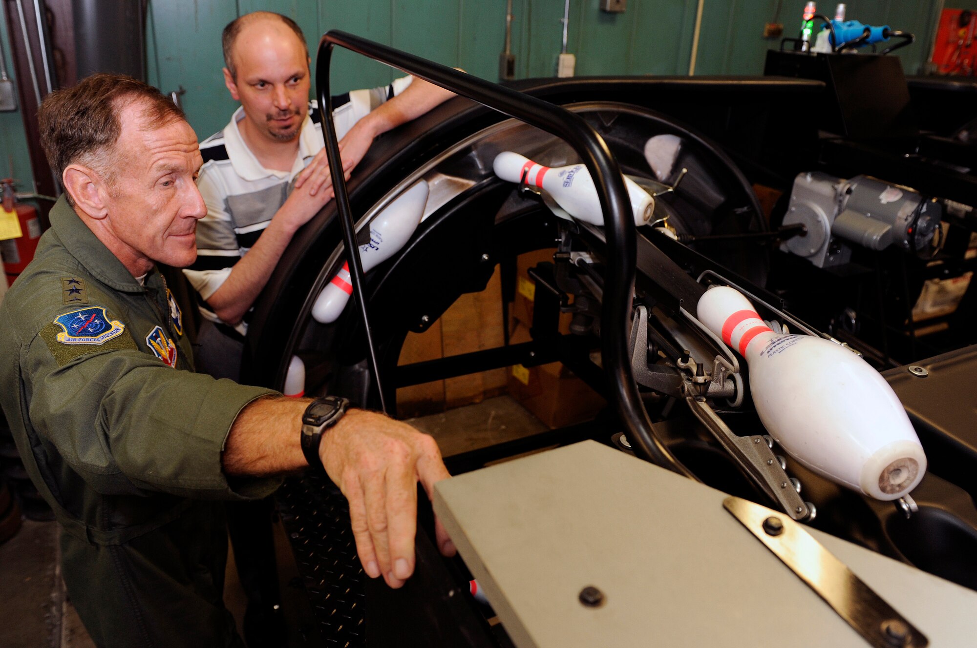 (Right) Kenneth Young, Ellsworth Bowling Center manager, demonstrates the AMF 90 XLi pin spotter to Lt. Gen. Norman Seip, 12th Air Force commander, during a visit, March 4. If there is a long delay between frames the pin spotters shut down to an energy-saving standby mode. (U.S. Air Force photo/Senior Airman Marc I. Lane)