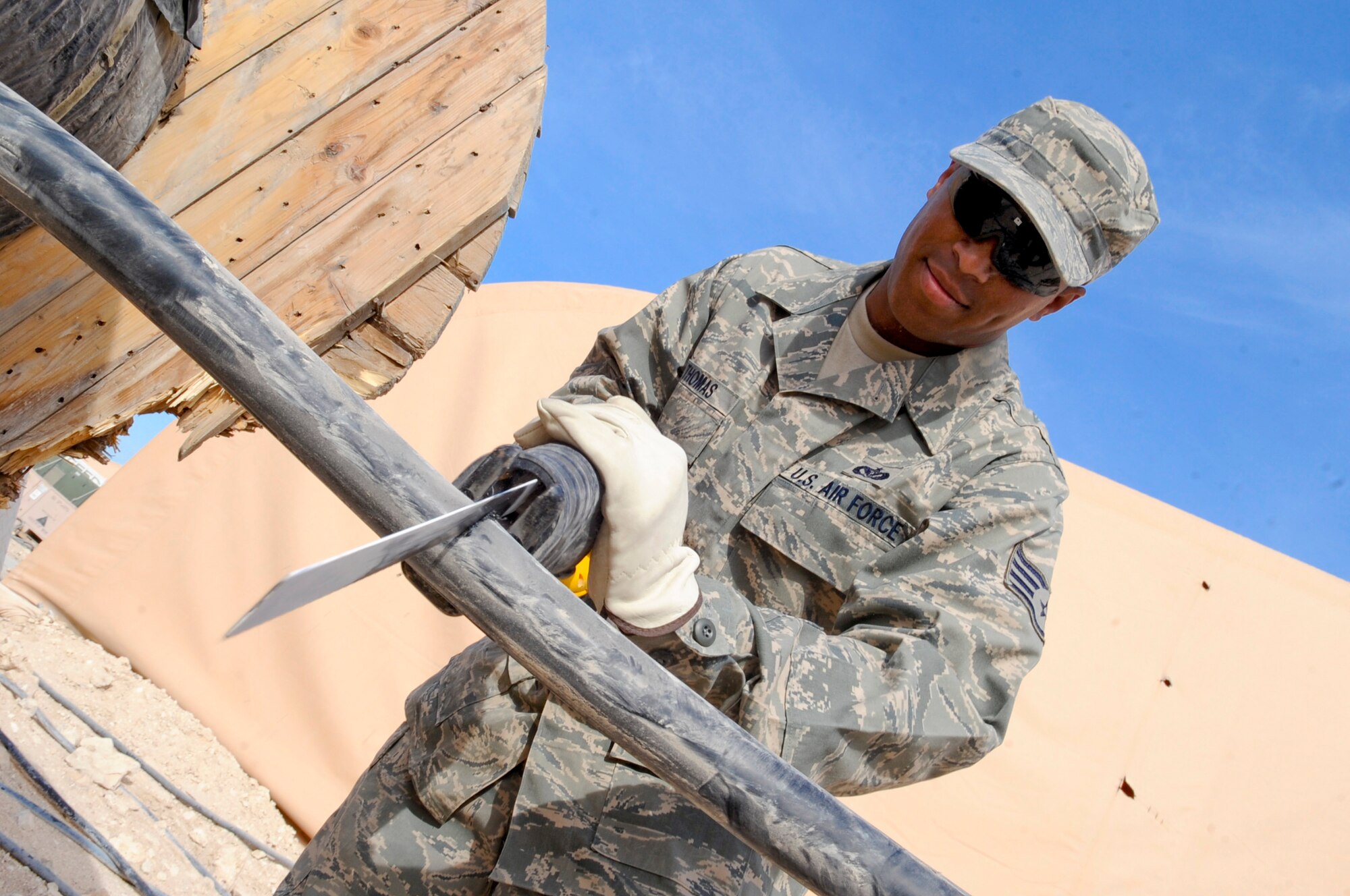 Staff Sgt. Michael Thomas, an electrician with the 379th Expeditionary Civil Engineer Squadron, uses a power saw to cut through high voltage cable, March 9, 2009, in an undisclosed location in Southwest Asia.  The cable will be used to switch buildings from generators to commercial power.  Sergeant Thomas is native to Valley, Ala. and is deployed McGuire Air Force Base, N.J., in support of Operations Iraqi and Enduring Freedom and Combined Joint Task Force - Horn of Africa.  (U.S. Air Force Photo by Staff Sgt. Joshua Garcia/released)