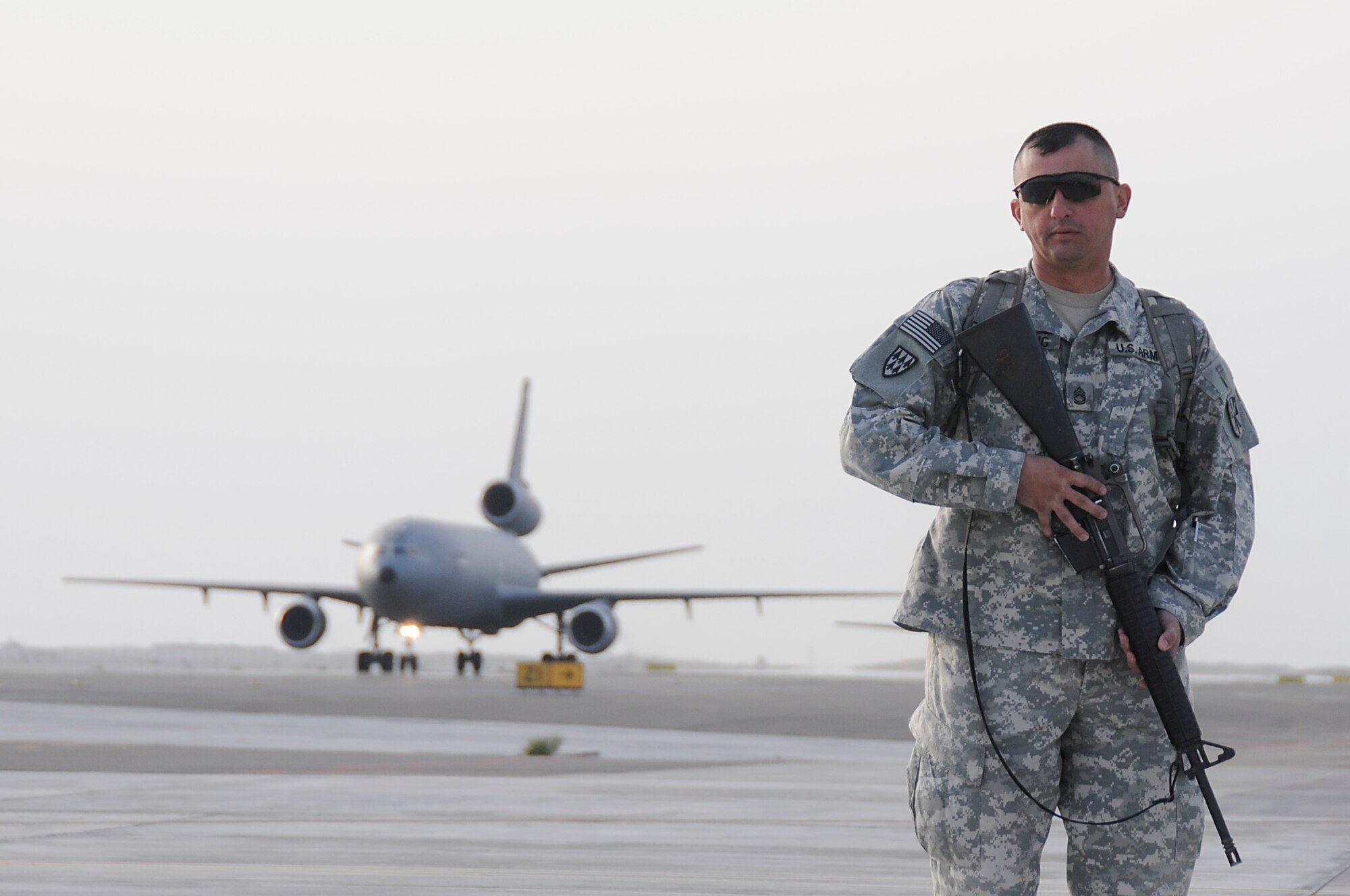 SOUTHWEST ASIA - A Soldier from the 5-52 Air Defense Artillery Battalion stands on the flightline of the 380th Air Expeditionary Wing as a KC-10 taxis in, Mar 5. Close to 200 Soldiers and several C-5 Galaxy's loaded with vehicles and equipment landed throughout the last few days as part of the first Patriot Battery mission for the wing, improving air defense capability. The Army will be incorporated into the 380th AEW's mission in support of Operations Iraqi and Enduring Freedom and Joint Task Force Horn of Africa. The 5-52 Air Defense Artillery Battalion is deployed out of Fort Bliss, TX. (U.S. Air Force photo by Senior Airman Brian J. Ellis)