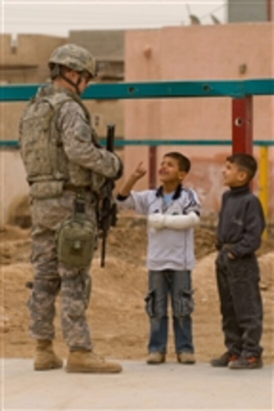 U.S. Army Spc. Benjamin Simpson from Bravo Company, 1st Battalion, 505th Parachute Infantry Regiment interacts with Iraqi children while providing flank security for Iraqi National Police officers during a visit to a school in the Doura district of Baghdad, Iraq, on March 1, 2009.  The officers are distributing clothing and soccer balls donated by American charities.  