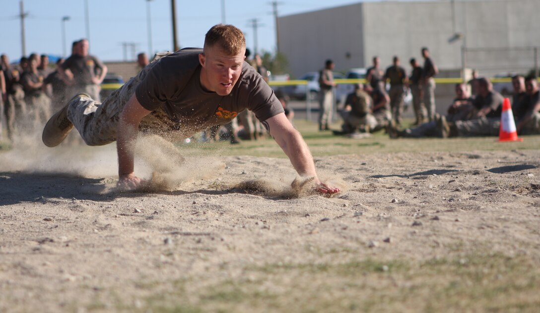 A Corporals Course student dives into the sand to begin low-crawling during the ‘maneuver under fire’ portion of the Combat Fitness Test that the Marines in the course participated in March 10.