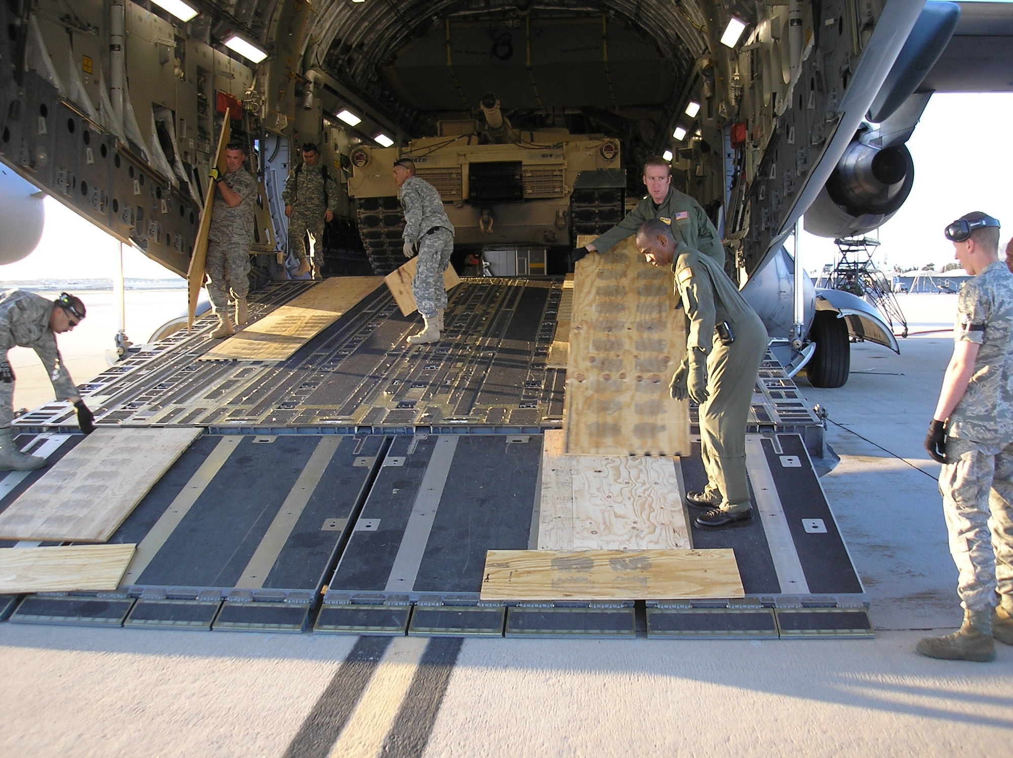 Members of the 452d TALCE, 50th and 56th Aerial Port Squadrons, and 729th Airlift Squadron remove boards used for traction in loading the M1 Abrams tank into a C-17. The tank was transported to March to train ground crews and aircrews to upload, off-load and fly the tank in preparation for upcoming deployments. (U.S. Air Force photos courtesy Tech. Sgt. Julie Stanyer)