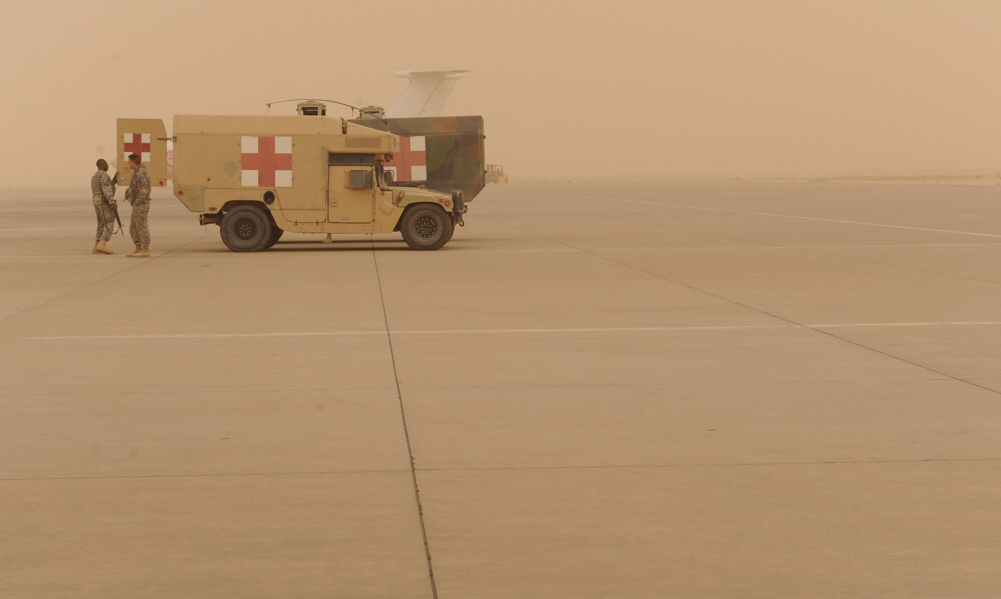 AL ASAD AIRFIELD, Iraq ? Two HMMWV ambulance varients wait on the parking apron of the airfield here to be marshalled to the back of a 777th Expeditionary Airlift Squadron C-130 Hercules to load patients. Airmen in the 332nd Expeditionary Aeromedical Evacuation Flight transport servicemembers wounded, injured or sick from remote locations to a higher level of medical care. (U.S. Air Force photo/Senior Airman Elizabeth Rissmiller) 