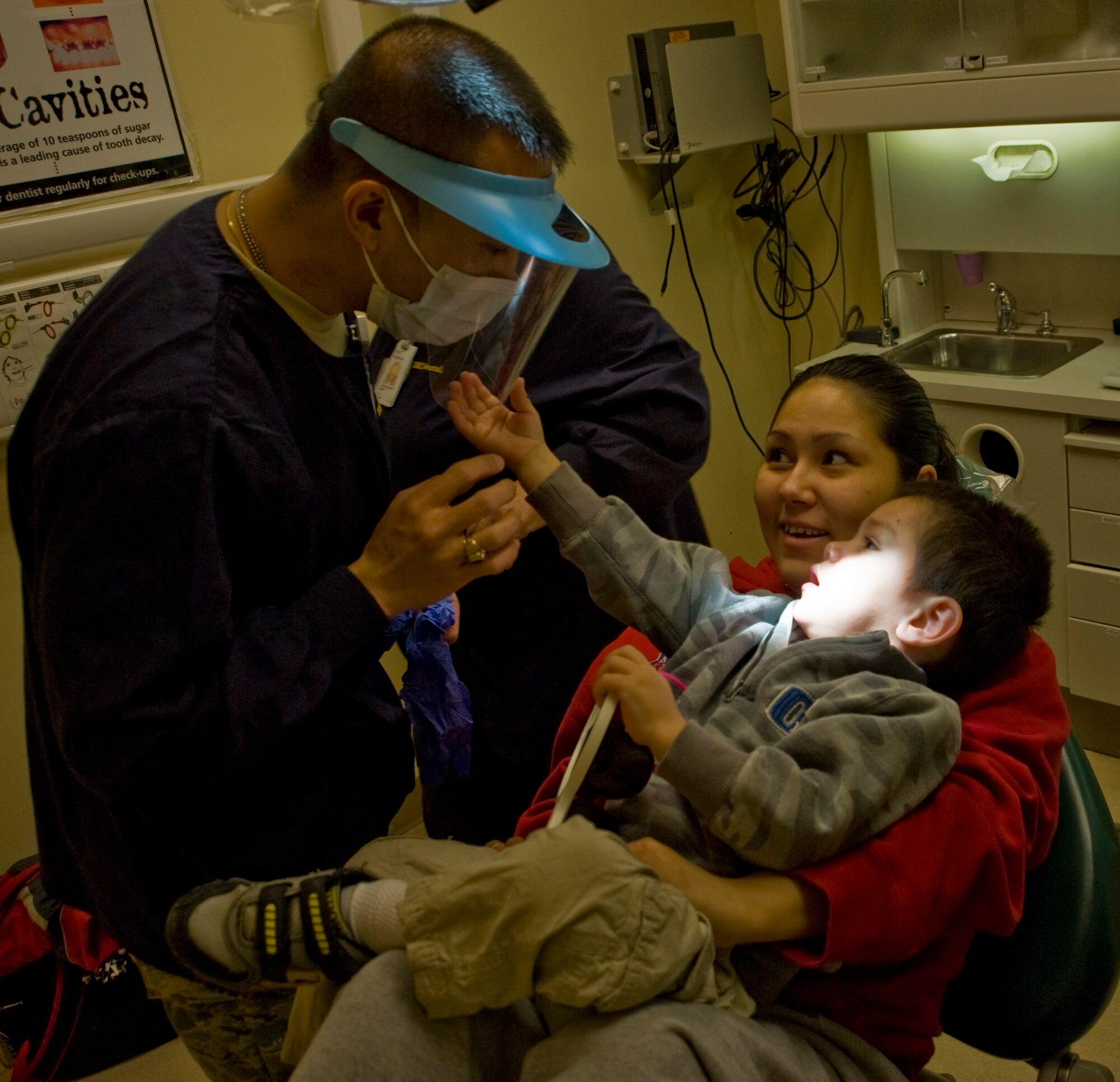 Maj. Lawrence Ngeryen of Rocklin, Calif., a staff dental officer at Travis Air Force Base, explains to a young patient the reason for wearing a protective visor while performing dental surgery at the Yukon-Kuskokwim Health Corporation clinic in Bethel, Alaska, on March 9, 2009. Operation Arctic Care is a joint military medical readiness exercise that brings no-cost health care to underserved Alaskan residents, including dental, optometry and veterinary support. This year's Navy-led mission has teams in 11 villages in Alaska's Yukon-Kuskokwim Delta region. (U.S. Air Force photo by Senior Airman Christopher Griffin)