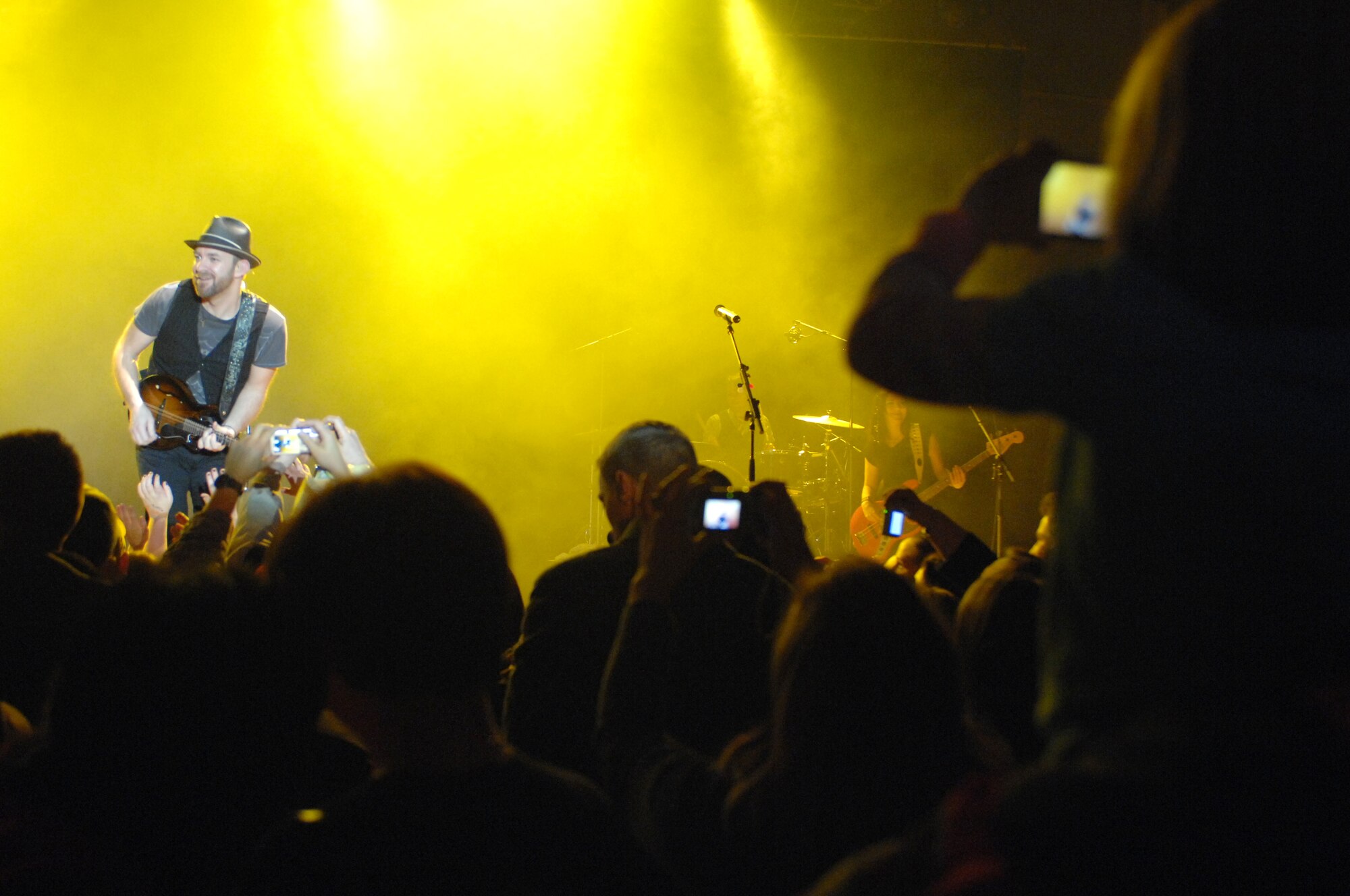 A young girl sits on her father's shoulders to capture a snapshot of Sugarland guitarist/vocalist, Kristian Bush during a concert March 6 in a hangar on the Aviano Air Base, Italy, flightline.  Sugarland's performance brought a little piece of home to the Aviano community during their first European performance. (U.S. Air Force photo/Airman 1st Class Tabitha M. Mans)   