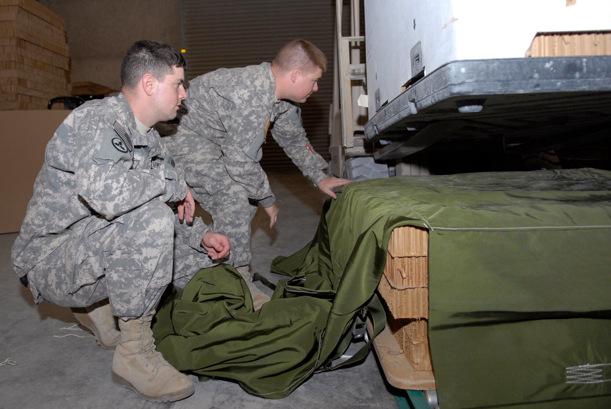 U.S. Army Sergeants David Kaspar and Daniel Billings, 824th Quartermaster Company Detachment 7 Riggers, ensure the commodity bundle is safely positioned on the container cover prior to being wrapped for an air drop to a base in the U.S. Central Command's area of responsibility (AOR), Mar. 9, 2009, at an undisclosed location in Southwest Asia.  Shipments of food, ammunition, and fuel prepared by the riggers can be destined for any coalition forces on the ground across the AOR.  Sgt. Kaspar hails from Fayetteville, Va.  Sgt. Billings hails from Raleigh, N.C.  Both are deployed from Fort Bragg, N.C. in support of Operations Iraqi and Enduring Freedom and Combined Joint Task Force - Horn of Africa.  (U.S. Air Force Photo by Senior Airman Andrew Satran/Released)