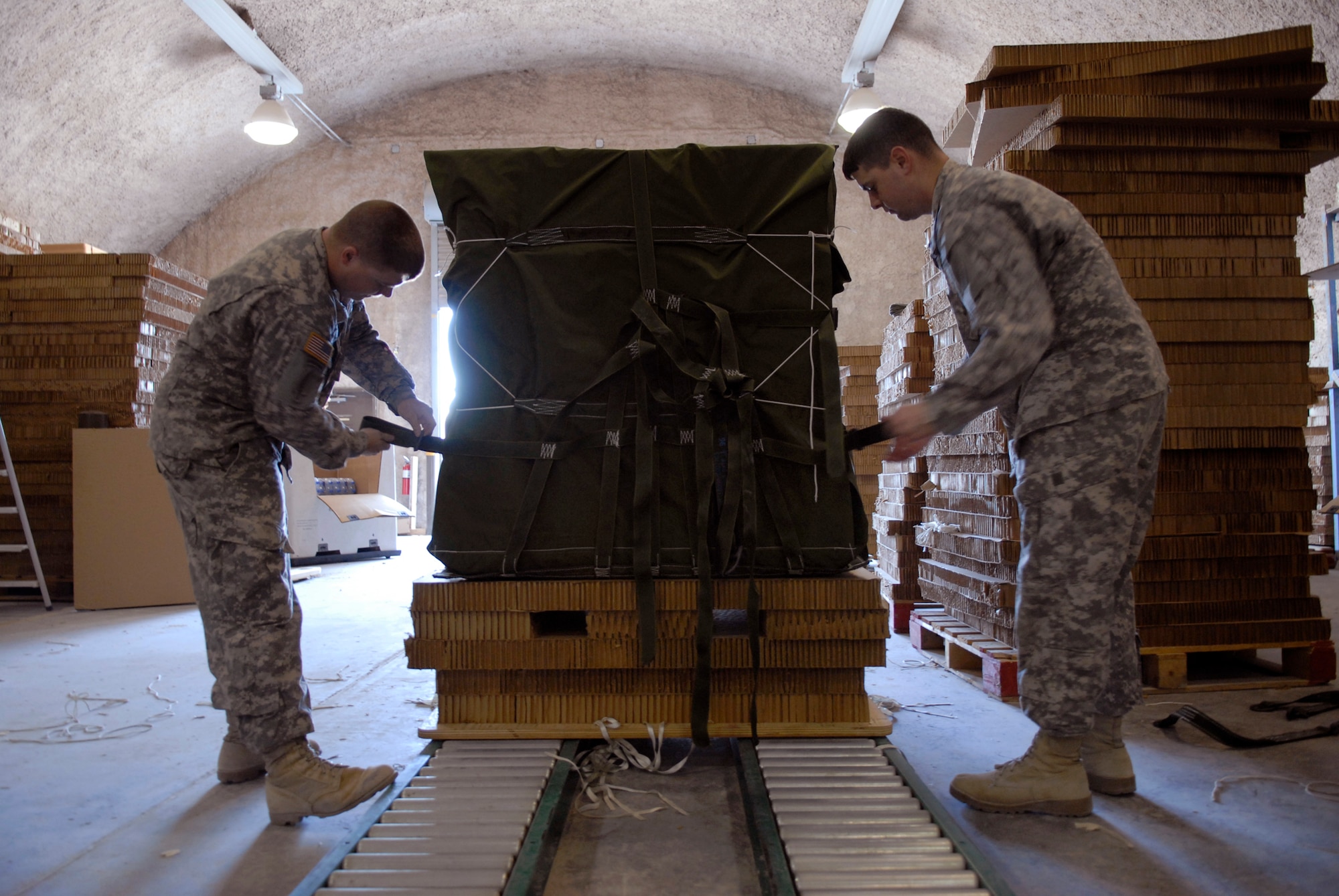 U.S. Army Sergeants Daniel Billings and David Kaspar, 824th Quartermaster Company Detachment 7 Riggers, tie 1/4 quarter inch cotton webbing around a commodity bundle in preparation for an air drop to a base in the U.S. Central Command's area of responsibility (AOR), Mar. 9, 2009, at an undisclosed location in Southwest Asia.  Shipments of food, ammunition, and fuel prepared by the riggers can be destined for any coalition forces on the ground across the AOR.  Sgt. Kaspar hails from Fayetteville, Va.  Sgt. Billings hails from Raleigh, N.C.  Both are deployed from Fort Bragg, N.C. in support of Operations Iraqi and Enduring Freedom and Combined Joint Task Force - Horn of Africa.  (U.S. Air Force Photo by Senior Airman Andrew Satran/Released)