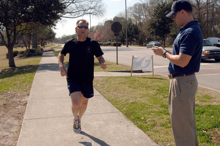 Shawn McKeen records time as Mike Bunting crosses the finish line during the Commander's Fitness Challenge 5,000-meter run here March 6. More than 350 Airmen from various squadrons participated in the run. Bunting was the first male to cross the finish line at 16:41 and is assigned to the 315th Maintenance Squadron. McKeen is assigned to the 437th Force Support Squadron. (U.S. Air Force photo/Staff Sgt. Marie Cassetty)
