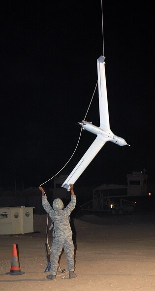 CAMP BUCCA, Iraq -- Senior Airman Quantral Fletcher, 887th Expeditionary Security Forces Squadron Scan Eagle maintainer, recovers a Scan Eagle unmanned aerial system after a test flight Feb. 25. The Scan Eagle does not land like a traditional aircraft. Intstead, a piece of equipment called a Sky Hook extends a bungee cord into the air which the UAS flies into. The cord slides across the edge of the wing until it's caught by a hook at the end of the wing. The UAS is then lowered to the ground and recovered. Airman Fletcher is originally from Memphis, Tenn. (U.S. Air Force photo by Staff Sgt. Thomas J. Doscher)