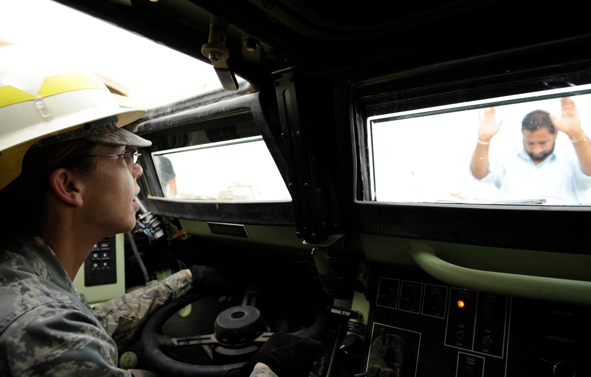 An Iraqi contractor motions Tech. Sgt. Julie Bottroff, 732nd Expeditionary Logistical Readiness Squadron, 586th Task Force, to halt after driving up on a semi truck in an armored security vehicle at Camp Liberty, Iraq Feb. 27. This vehicle is a part of a convoy going to Kuwait with approximately 30 semi trucks loaded with all types of military vehicles. Sergeant Bottroff is a Joint Expeditionary Tasking airman who is the yard boss of the Redistribution Property Assistance Team. The personnel at the yard have processed more than a $1 billion of inventory for the Army through their six month deployment. Sergeant Bottroff is a native of Oklahoma City, Olka. and is deployed from Shaw Air Force Base, S.C. where she is a medical administrator.  (U.S. Air Force photo by Senior Airman Jacqueline Romero)
