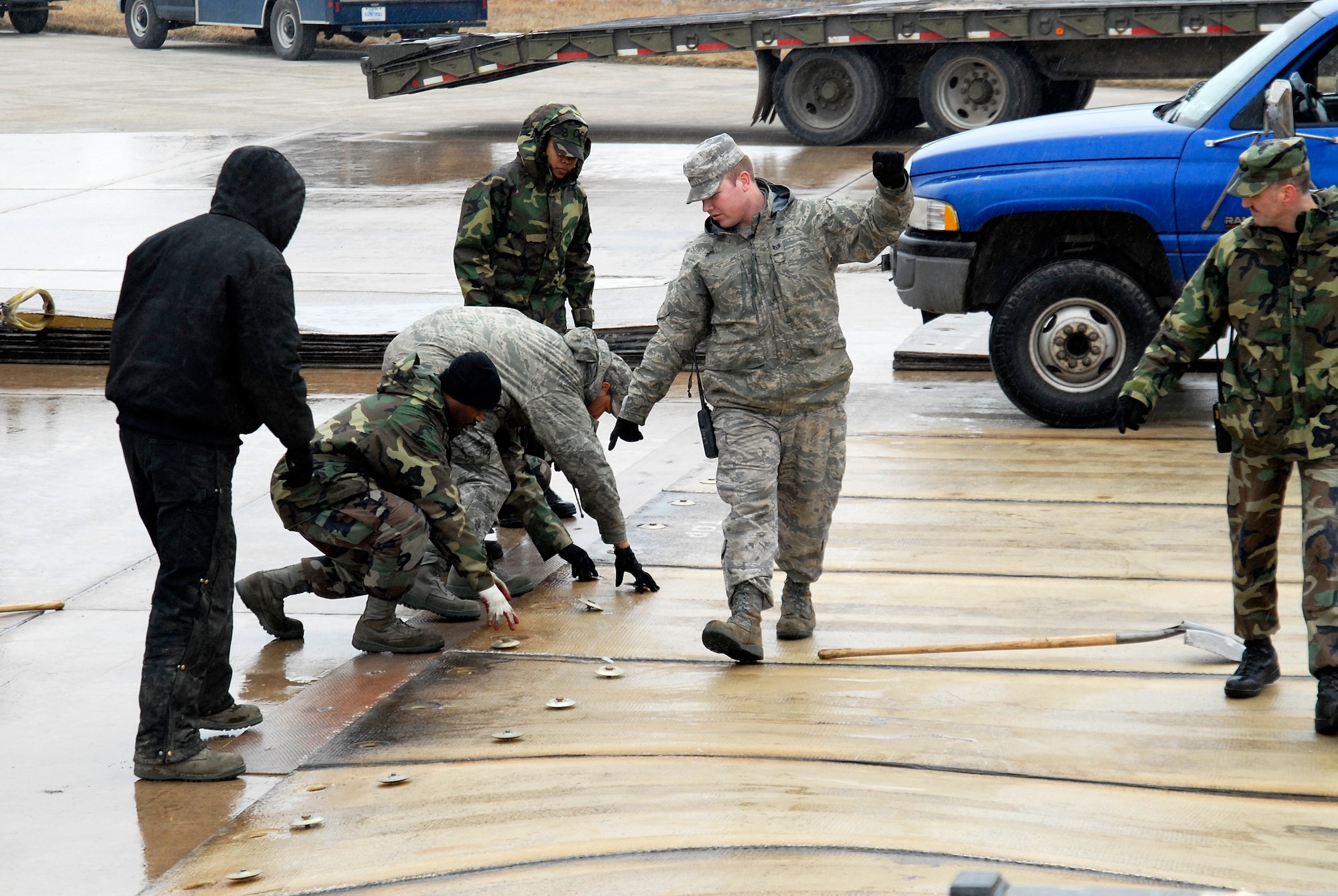 Staff Sgt. Christopher Roberts, 8th Civil Engineer Squadron, simultaneously directs a forklift and members of the Fiberglass Matt Team to move during an Airfield Damage Repair exercise at Kunsan Air Base, Republic of Korea, March 5, 2009. ADR is a temporary fix on damage caused to the airfield by enemy fire to allow aircraft to quickly get back in the air. (U.S. Air Force Photo by SSgt Jason Colbert)