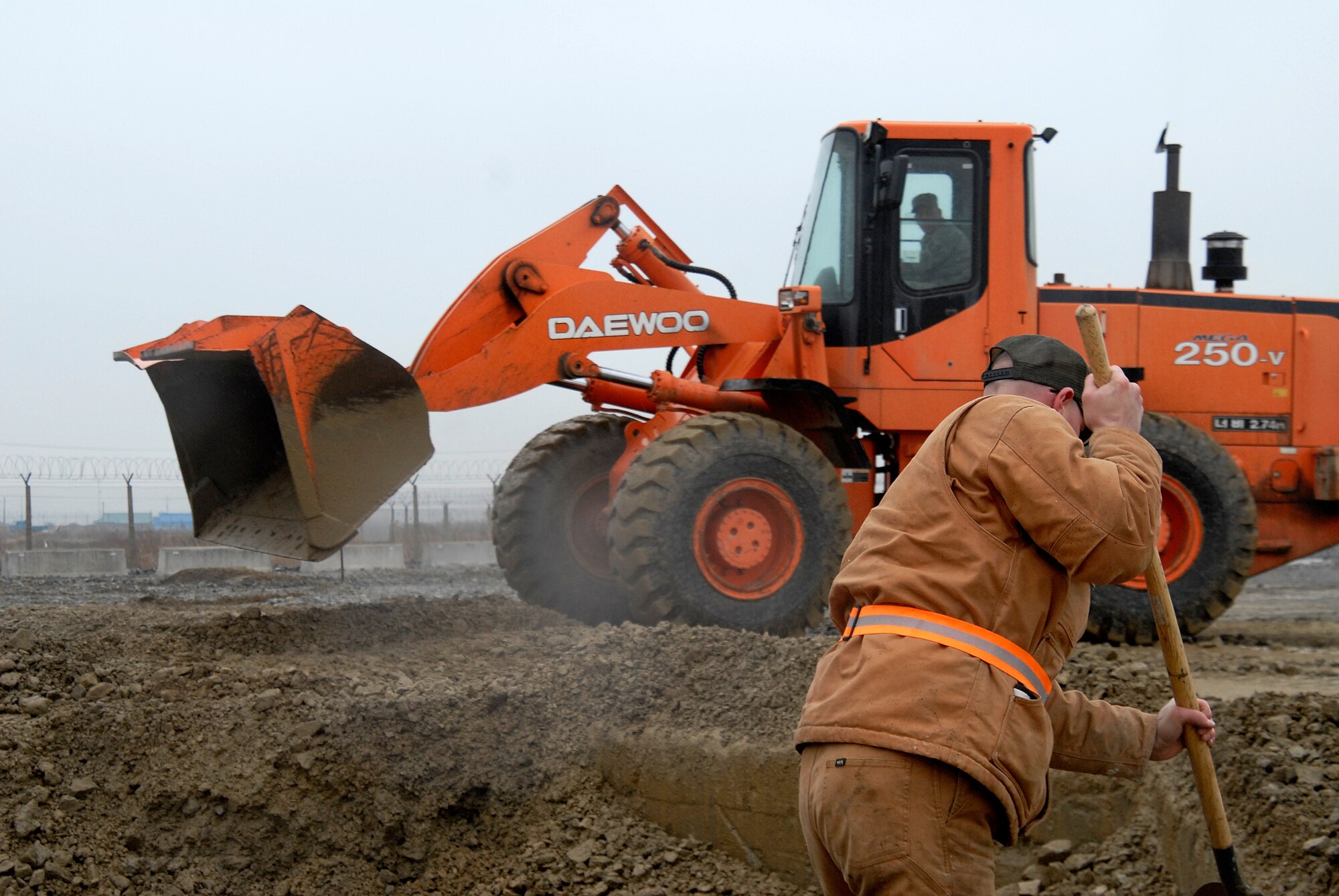 Senior Airman Brad Schrage (foreground), 8th Civil Engineer Squadron, begins filling in a crater as Staff Sgt. Gary Cochran clears dirt from around a it using a 2.5 yard bucket loader during an Airfield Damage Repair exercise at Kunsan Air Base, Republic of Korea, March 5, 2009. ADR is a temporary fix on damage caused to the airfield by enemy fire to allow aircraft to quickly get back in the air. (U.S. Air Force Photo by SSgt Jason Colbert)