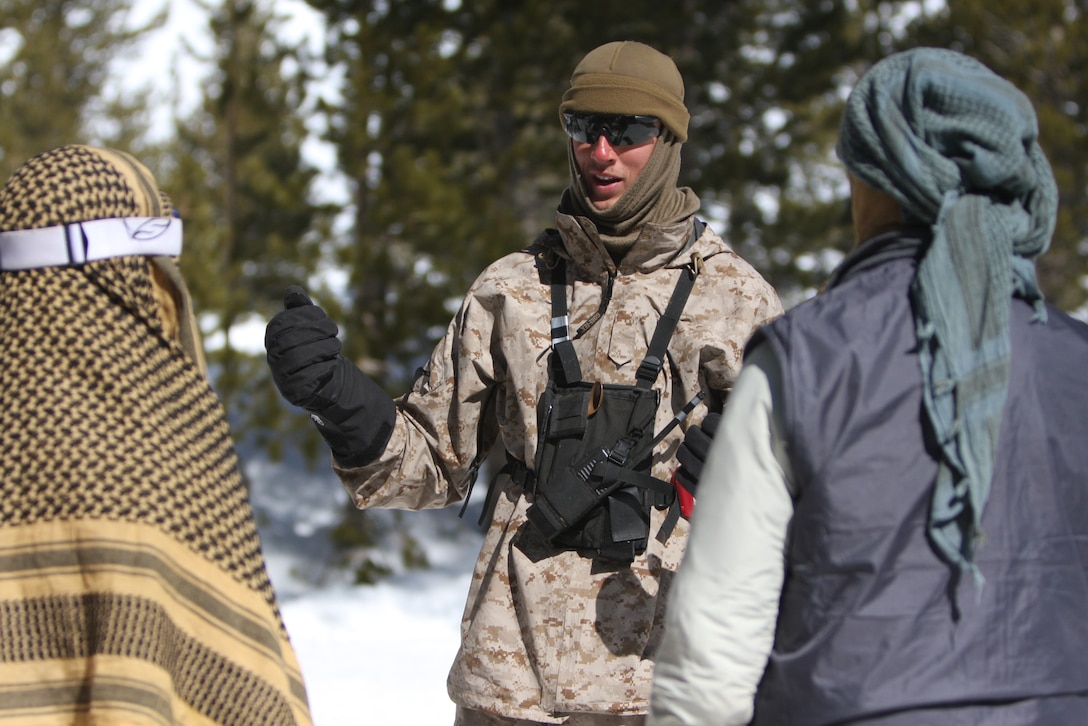 Cpl. John G. Hatcher, an instructor with the Unit Training Group at the Marine Corps Mountain Warfare Training Center Bridgeport, Calif., reviews the outlined roles being played by two Afghani role player Marines with 3rd Combat Engineers Battalion, based out of the Combat Center, at training area Penguin March 12.