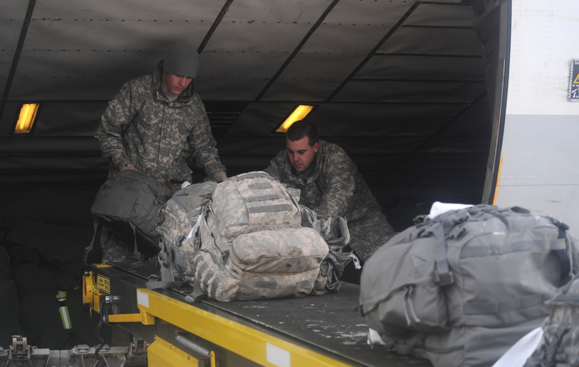 ELMENDORF AIR FORCE BASE, Alaska -- Army Spc. Lance Fisher and Army Pvt. Adam Jacobs assist the 732nd Air Mobility Squadron ground crew in stacking bags on the contracted airliner, which is transporting their unit, 2377th P4 Alpha Battery, to Iraq March 10, 2009. Fisher and Jacobs are apart of the unit's deployment transition team sent to help 732th AMS in getting their unit ready to deploy. (U.S. Air Force photo/ Senior Airman Matthew Owens)