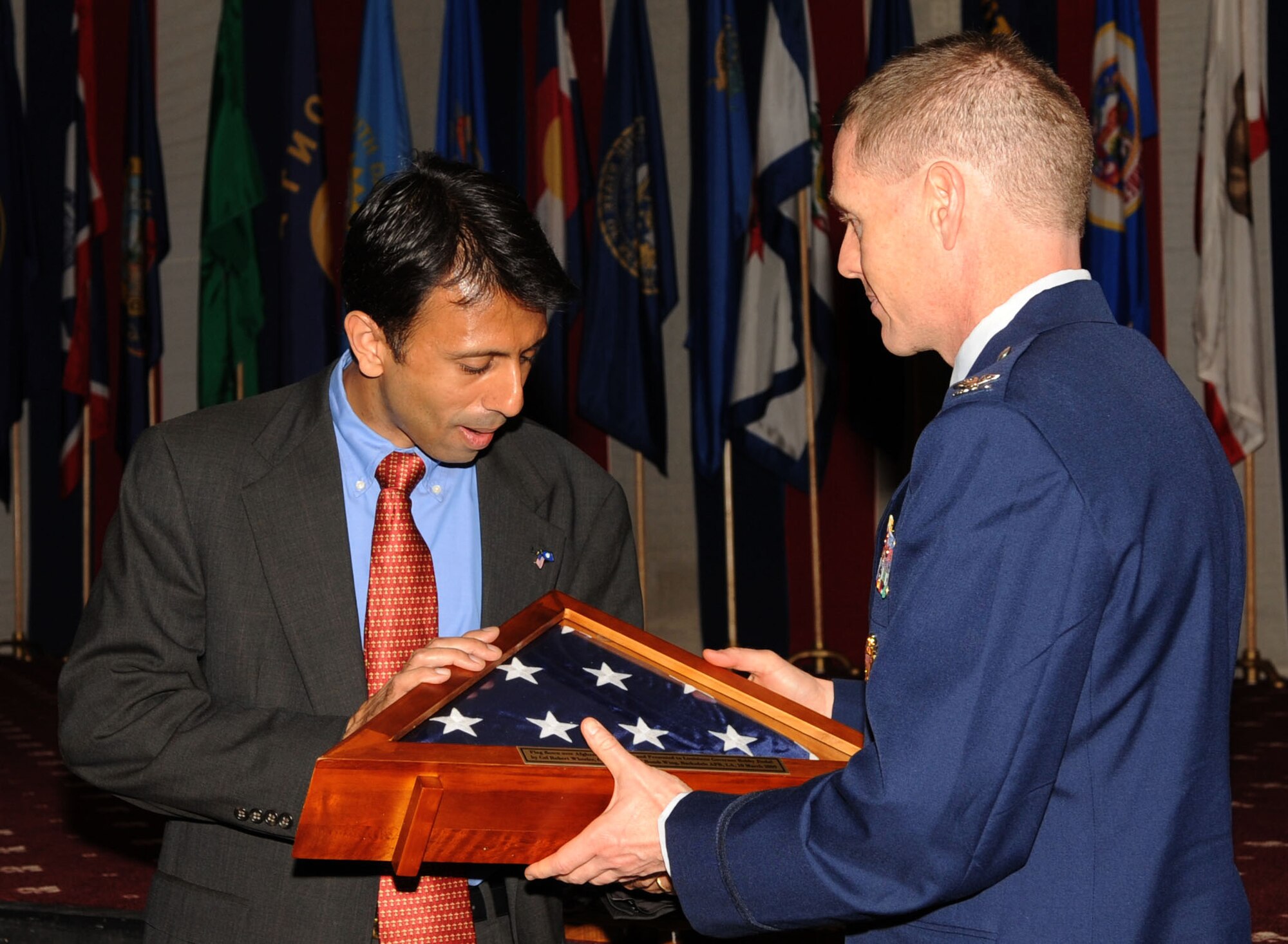 Col. Robert Wheeler, 2d Bomb Wing commander, presents a cased flag to Louisiana Gov. Bobby Jindal during the medal presentation for veterans at Hoban Hall.  (Senior Airman Alexandra Sandoval/U.S. Air Force ) 