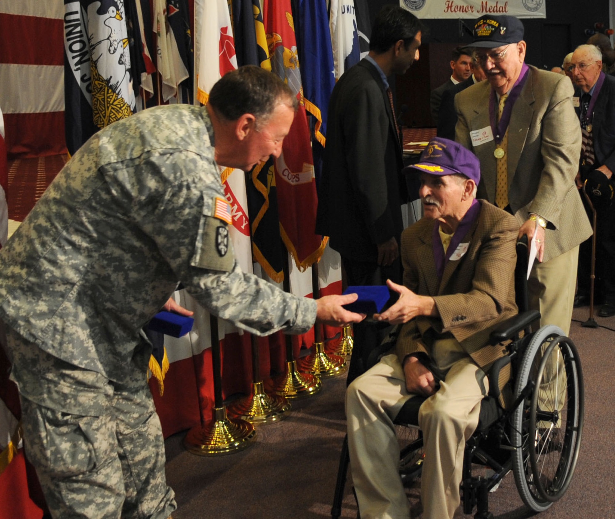 Maj. General Bennett Landreneau, adjutant general for Louisiana State National Guard, hands out the boxes for the ribbons to two Purple Heart recipients during the ceremony for the new Louisiana Veterans Honor Medal. (Senior Airman Alexandra Sandoval/U.S. Air Force ) 