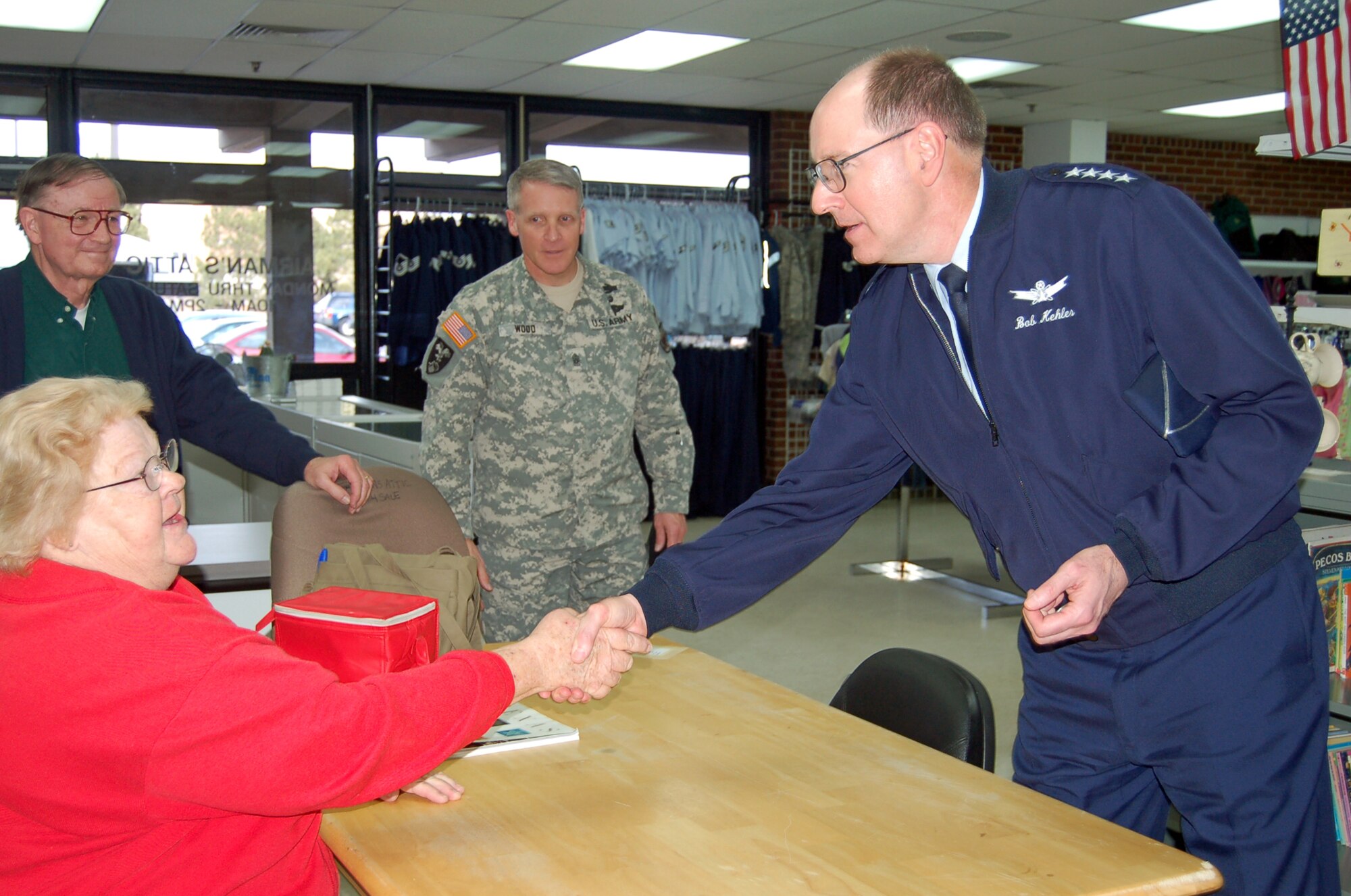Gen. C. Robert Kehler, Air Force Space Command commander at Peterson Air Force Base shakes the hand of Sandra Trean, Airman’s Attic volunteer before handing her a Guardians of the Higher Frontier coin at the "Attic" Feb. 23. Airman’s Attic marked a one year anniversary in a new location in February. The Airman’s Attic is co-located with the Family Service loan closet at building 1425, across the parking lot from the base chapel. (Photo by Thea Skinner)