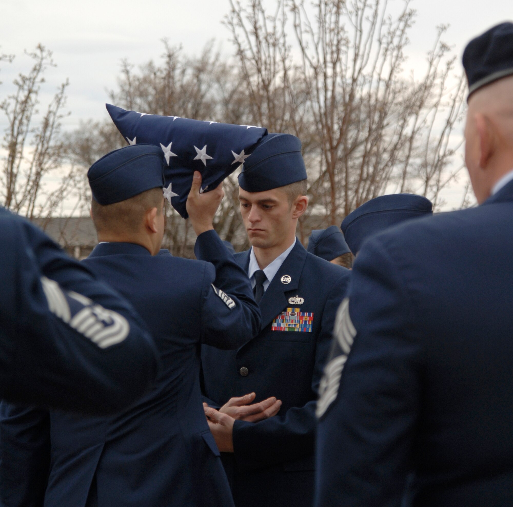 MCCONNELL AIR FORCE BASE, Kan. -- Staff Sgt. Dustin Swanson, 22nd Aircraft Maintenance Squadron, prepares to receive a folded American flag from Master Sgt. Edgar Salazaraguirre, 184th Air National Guard, during a retreat ceremony held in Col. Michael V. Krueger’s honor outside building 1, March 9. The ceremony consisted of lowering the American flag flown aboard a KC-135R during a refueling mission over Afghanistan and Iraq in support of Operations Enduring Freedom and Iraqi Freedom. It will be given to Colonel Krueger’s family. (Photo by Senior Airman Laura Suttles)