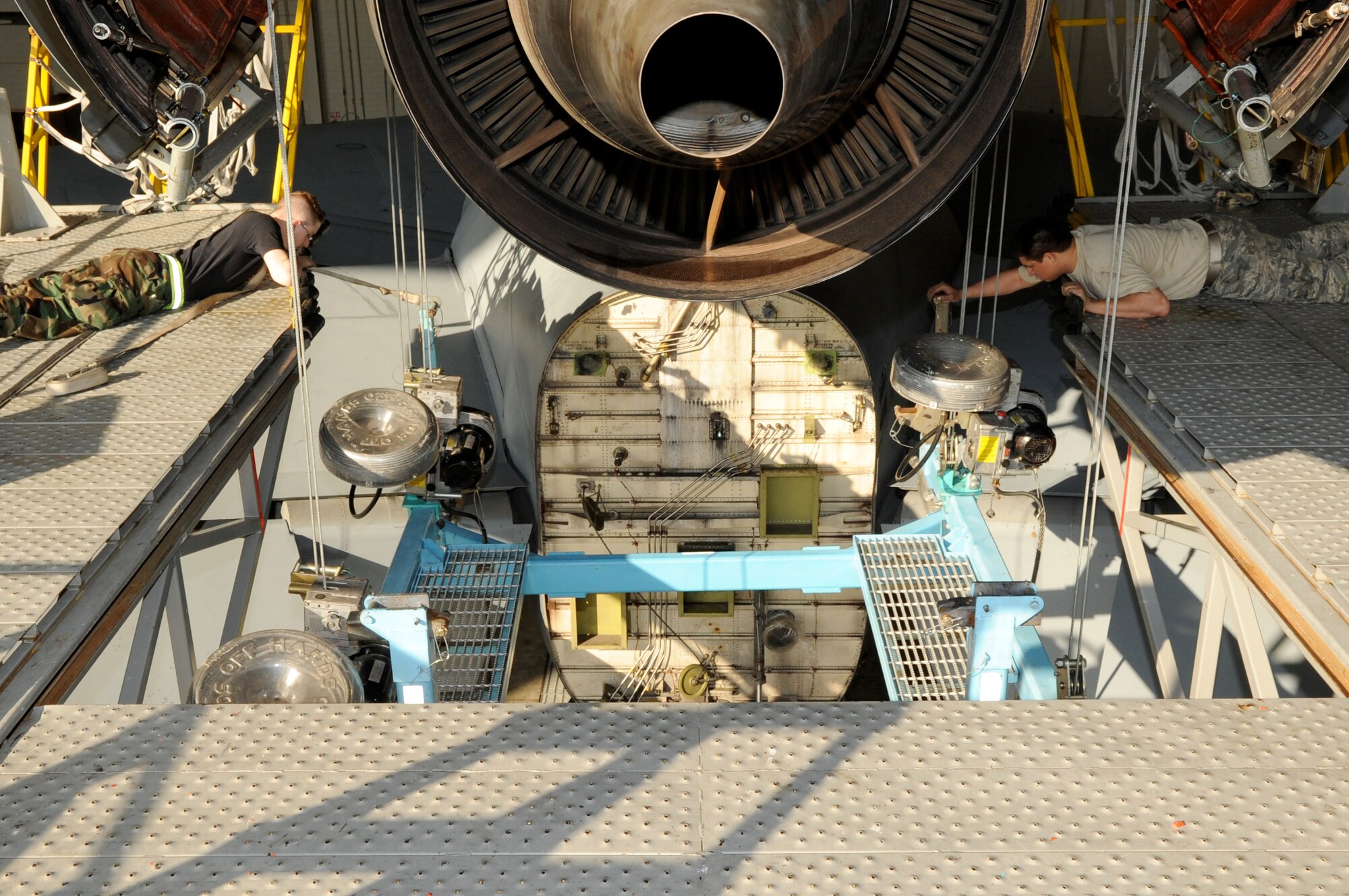 As part of the engine change stand is slowly hoisted up to the engine, Senior Airman Robert Duncan, 605th Aircraft Maintenance Squadron, and Senior Airman Rafael Lopez, 714th Aircraft Maintenance Squadron, steady the cart into place March 6. Once the cart is attached and ready to support the engine, the maintainers then remove the six engine mount bolts -- the only thing holding an engine to the aircraft -- and lower the cart back down to the wheeled base with the bad engine. The reverse is done with a good engine. An engine change, from start to finish with engine drop to operational check, takes three days. (U.S. Air Force photo/Wayne Russell)