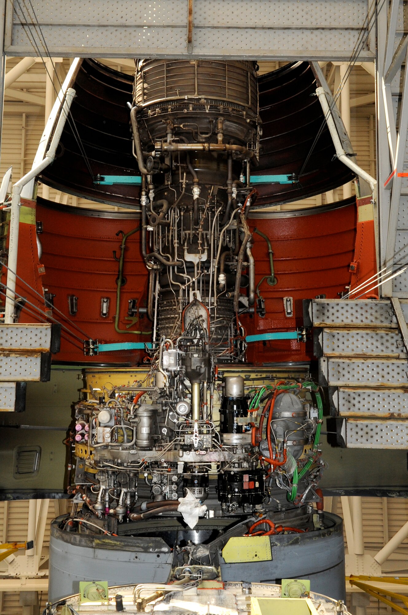 From the rear of a KC-10A facing forward looking two stories up, the engine, with cowl doors open, is ready to come down. On the KC-10, the tail cone section and parts of the elevator can be dropped to make room for the engine to be dropped. Even the maintenance tail stand has a rollaway center and sliding side just for the purpose of engine removal. (U.S. Air Force photo/Wayne Russell)
