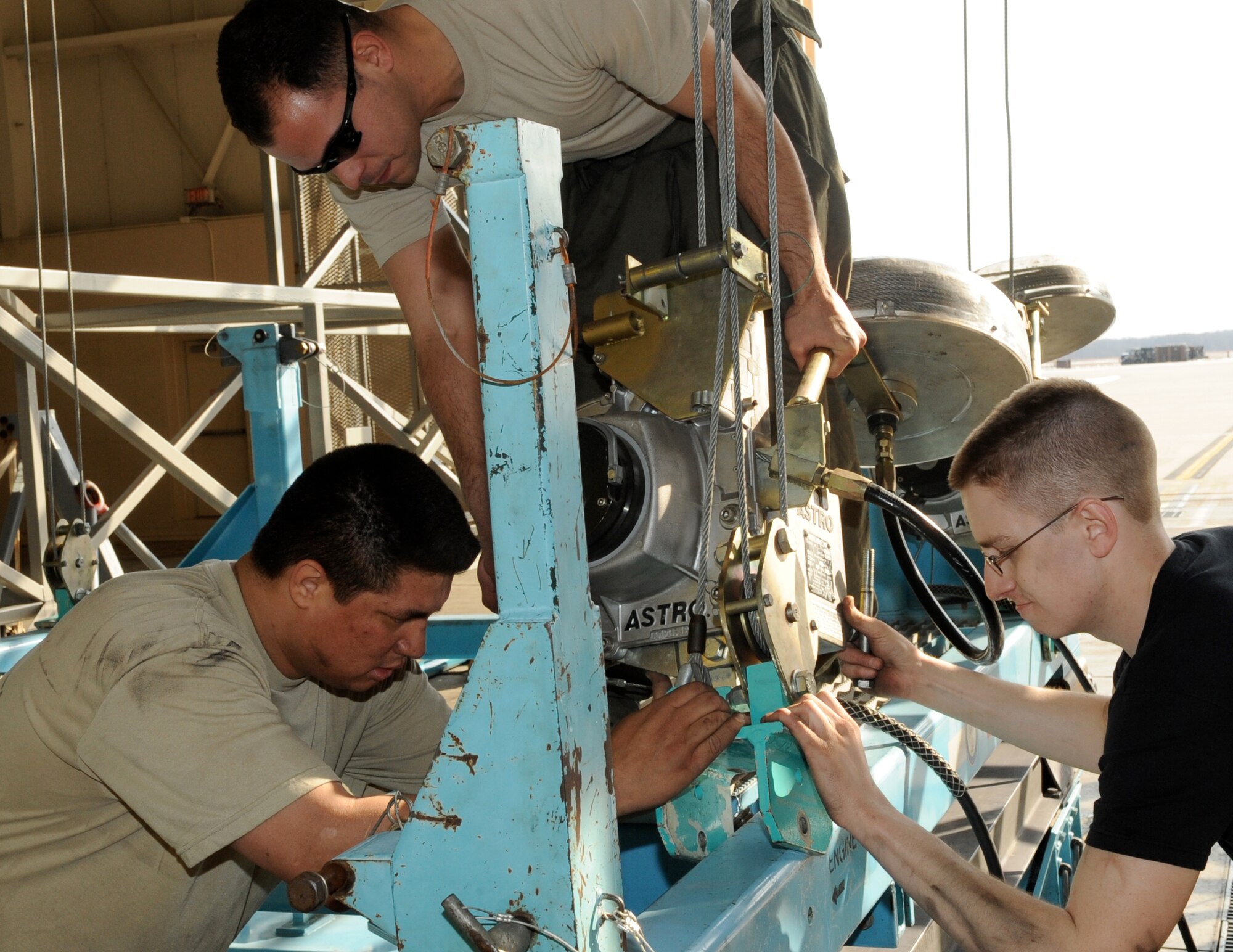 Left to right, Senior Airman Rafael Lopez, 714th Aircraft Maintenance Squadron, Staff Sgt. Aguedo Mendez, and Senior Airman Robert Duncan, both of the 605th Aircraft Maintenance Squadron, work as a team to start connecting the hoists to the engine change cart March 6. Members of the Reserve 714th AMXS, like Airman Lopez, play vital roles in daily operations working side-by-side with their active-duty counterparts in the 605th AMXS. (U.S. Air Force photo/Wayne Russell)