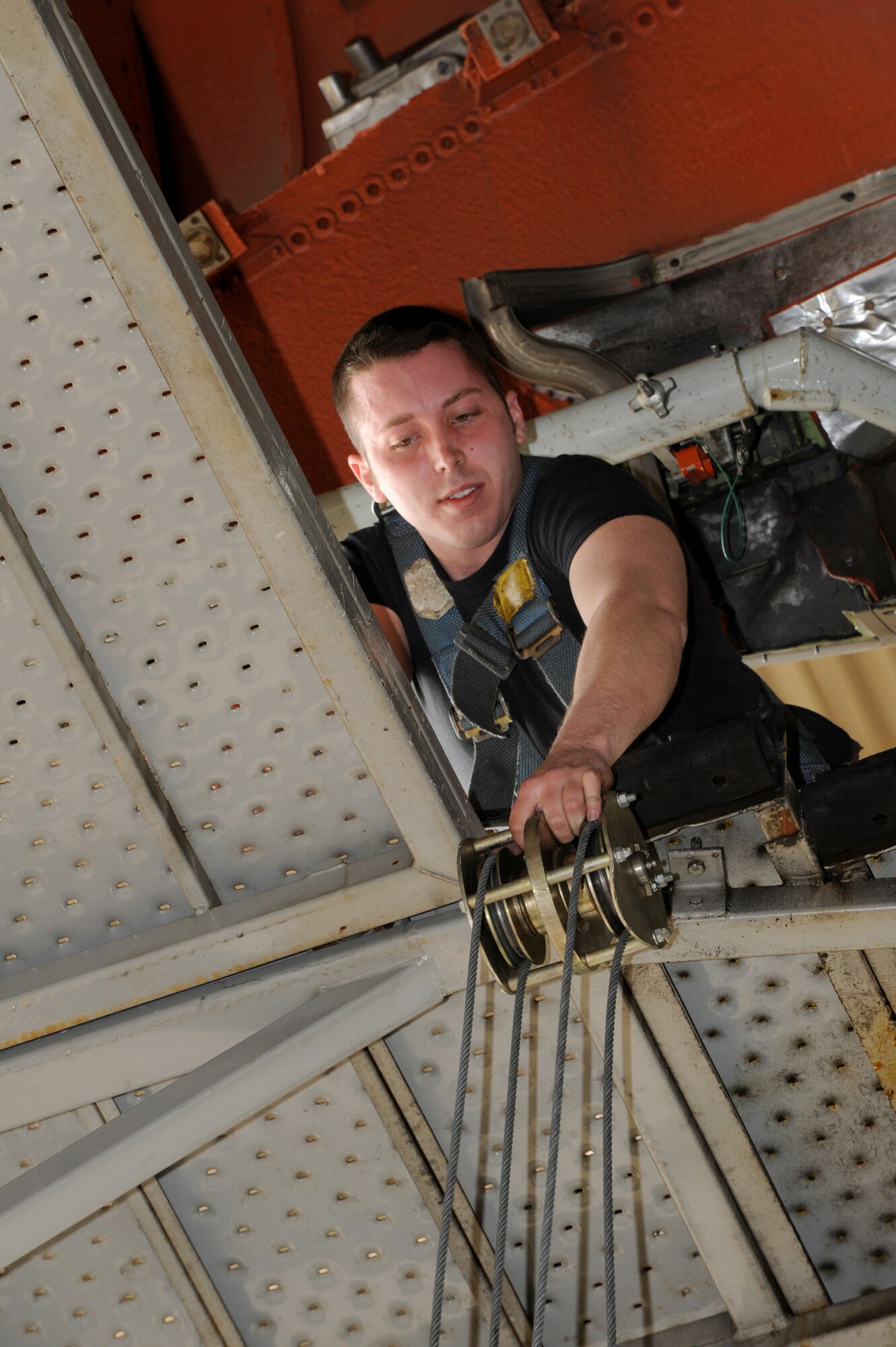 With a safety harness securing him to the two story “Tail Stand,” Airman 1st Class Aaron Keeling, 605th Aircraft Maintenance Squadron Jet Shop mechanic, pulls up the rear hoist to connect to the CF6-50C2 -- the #2 Engine on a KC-10A March 6. The engine can cost $5 million brand new, but a repaired/overhauled engine can cost about $2 million, which saves $3 million dollars. (U.S. Air Force photo/Wayne Russell)  