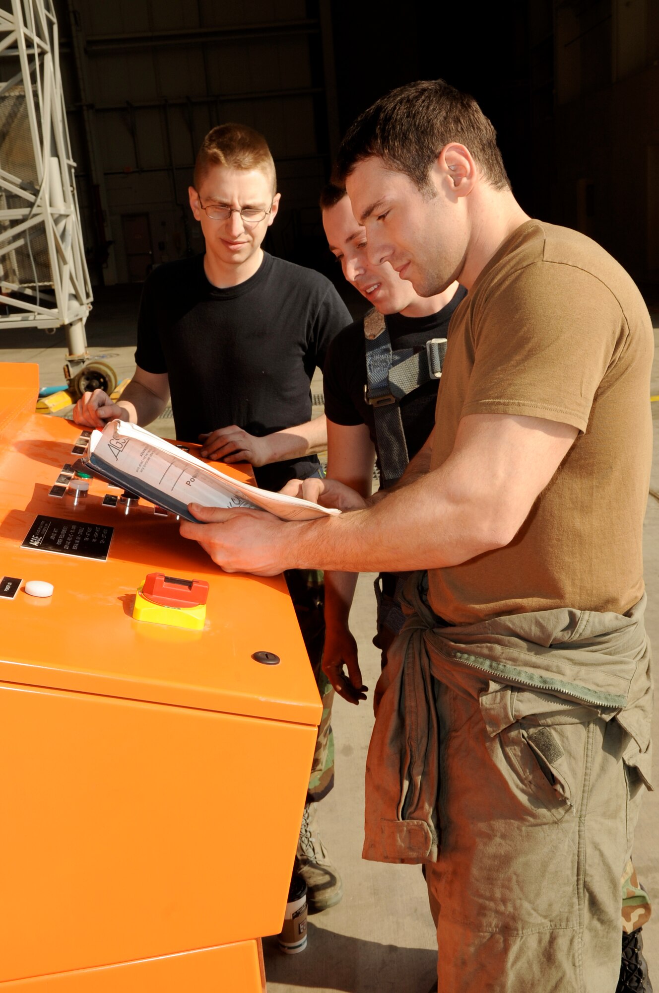 Left to right, Senior Airman Robert Duncan, Airman 1st Class Aaron Keeling, and Staff Sgt. Jaime Sherwood, all from the 605th Aircraft Maintenance Squadron Jet Shop, go over safety procedures of the Powered Bootstrap System, which controls and distributes power to three different hoists to lift and lower a #2 engine on a KC-10A March 6. The engine was found to have a damaged turbine during a periodic inspection of the aircraft. (U.S. Air Force photo/Wayne Russell)