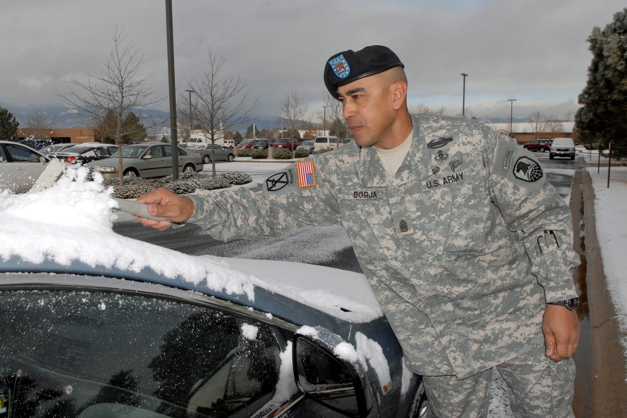 CSM Ralph C. Borja, Command Sgt. Maj. for SMDC/ARSTRAT, takes the time to clean off his rental car prior to travel during March 10's surprise snow flurries. 
Clearing accumulated snow off your vehicle is one of the first things that should be done before hitting the road. “Safety is a priority anywhere for any vehicle during adverse conditions”  stated CSM Borja as he was sweeping away the snow. “It’s best to be prepared”.  Followed by April, March is the heaviest snowfall month due to the unique Colorado Divide weather. It’s in your, and your family’s, best interests to continue to plan for cold weather until early summer.  Plan to be safe now; not sorry later. Stay vigilant and alive.  (Photo by Rob Bussard)