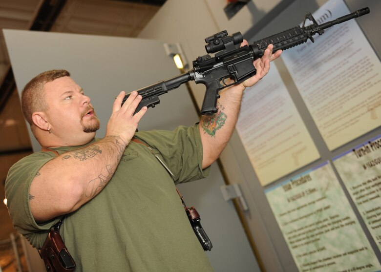 SCOTT AIR FORCE BASE, Ill. --Mr. Hampton inspects the “68”, the aiming device that is used on the M-4 carbine which is used in place of the traditional iron sights. The aiming device features a red dot laser point and boasts greater aiming and accuracy capabilities. (U.S. Air Force photo/Staff Sgt. Paul Villanueva)