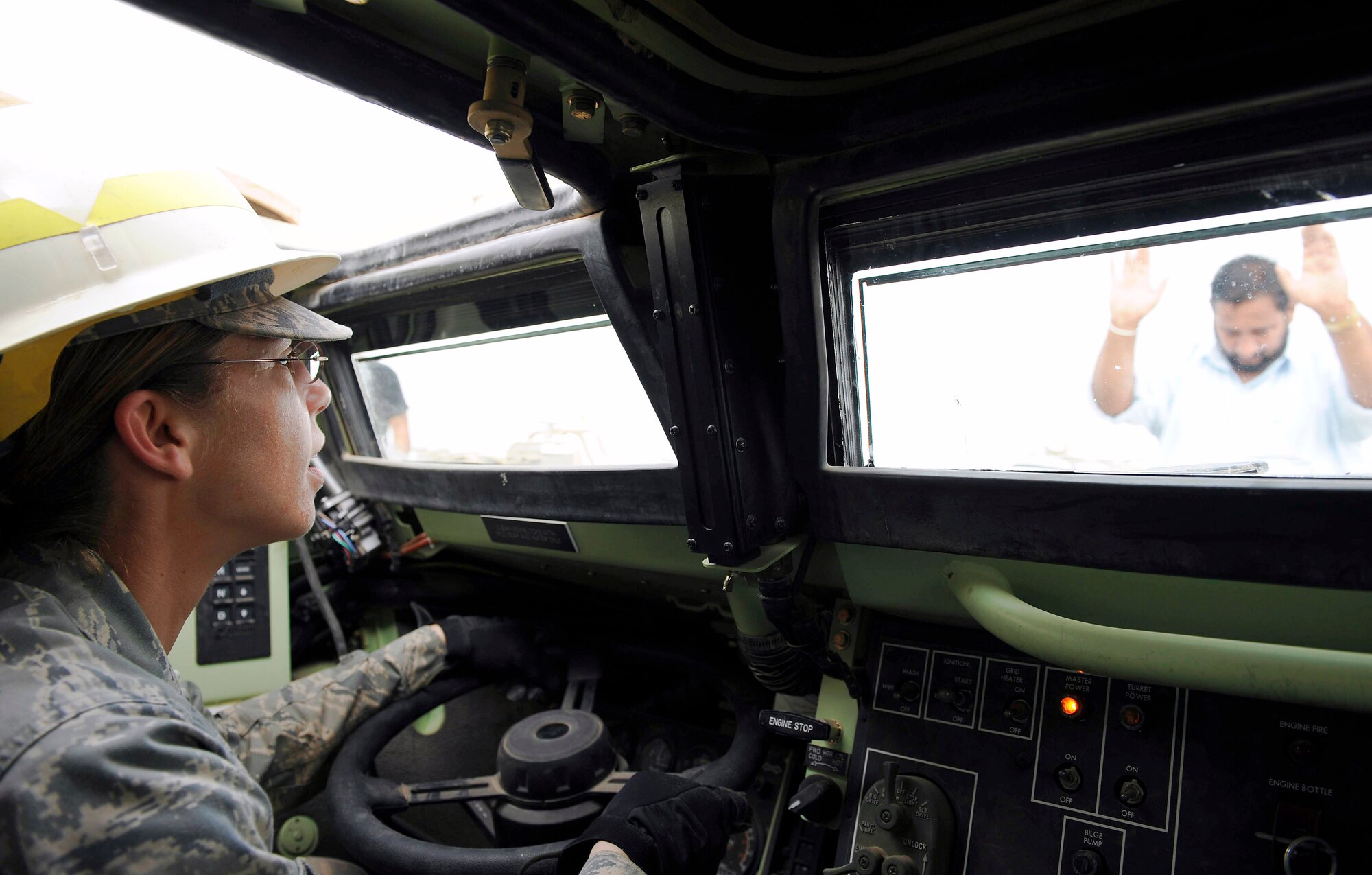 An Iraqi contractor motions Tech. Sgt. Julie Bottroff to halt after driving up on a semitruck in an armored security vehicle Feb. 27 at Camp Liberty, Iraq. This vehicle is a part of a convoy going to Kuwait with approximately 30 semitrucks loaded with all types of military vehicles. Sergeant Bottroff is assigned to the 732nd Expeditionary Logistical Readiness Squadron, 586th Task Force.  She is a native of Oklahoma City and deployed from Shaw Air Force Base, S.C. (U.S. Air Force photo/Senior Airman Jacqueline Romero)