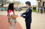 Mariah Bussey, a Randolph Girl Scout, hands a folded flag to Col. Jacqueline Van Ovost, 12th Flying Training Wing commander, after the troops performed a retreat ceremony on March 10. (U.S. Air Force photo by Steve White)